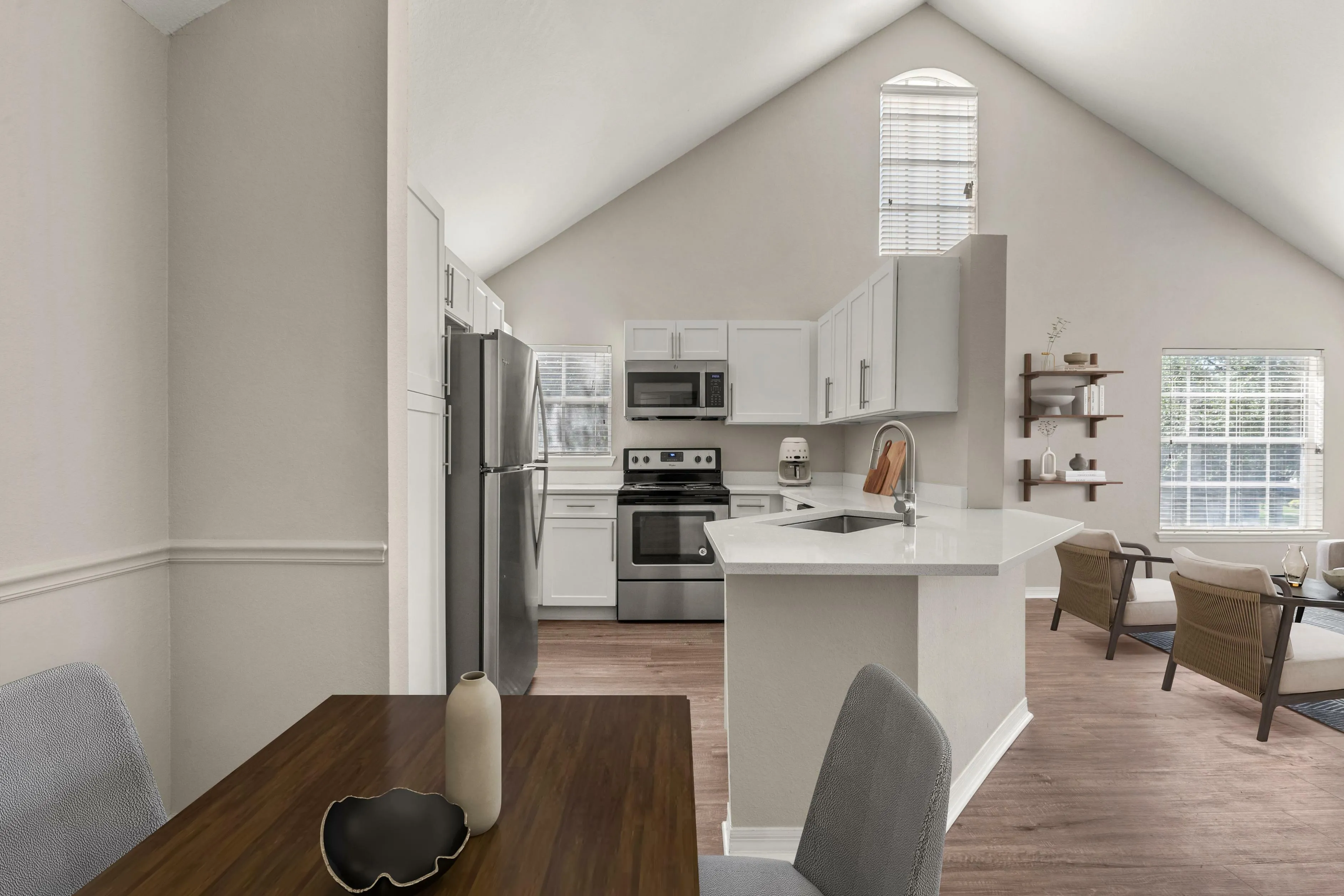 Bright and airy open-plan apartment kitchen with modern stainless steel appliances, elegant white cabinetry, and a cozy dining area.