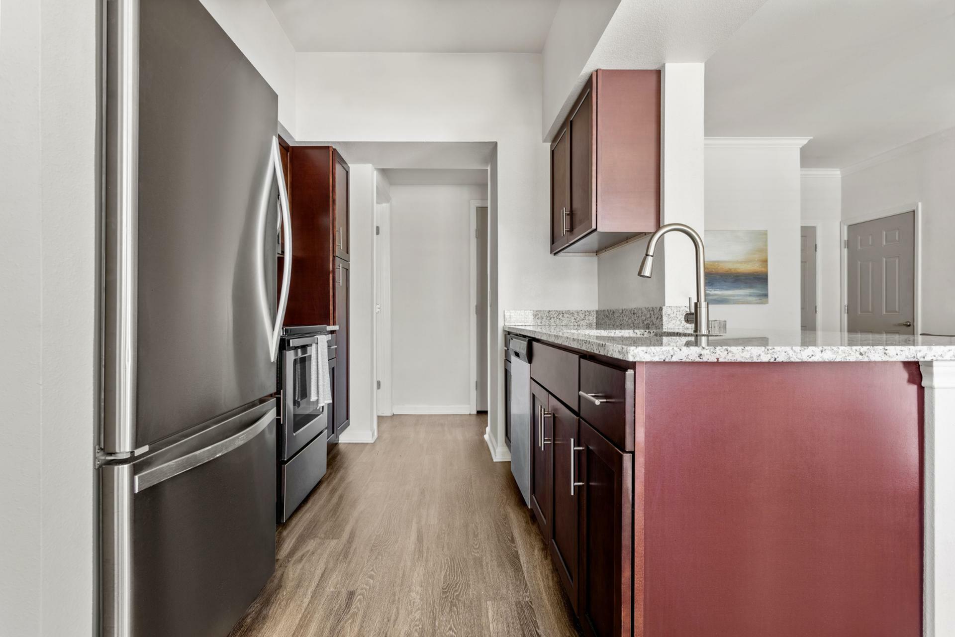 Modern kitchen with sleek stainless-steel appliances, rich wood cabinetry, and elegant granite countertops.