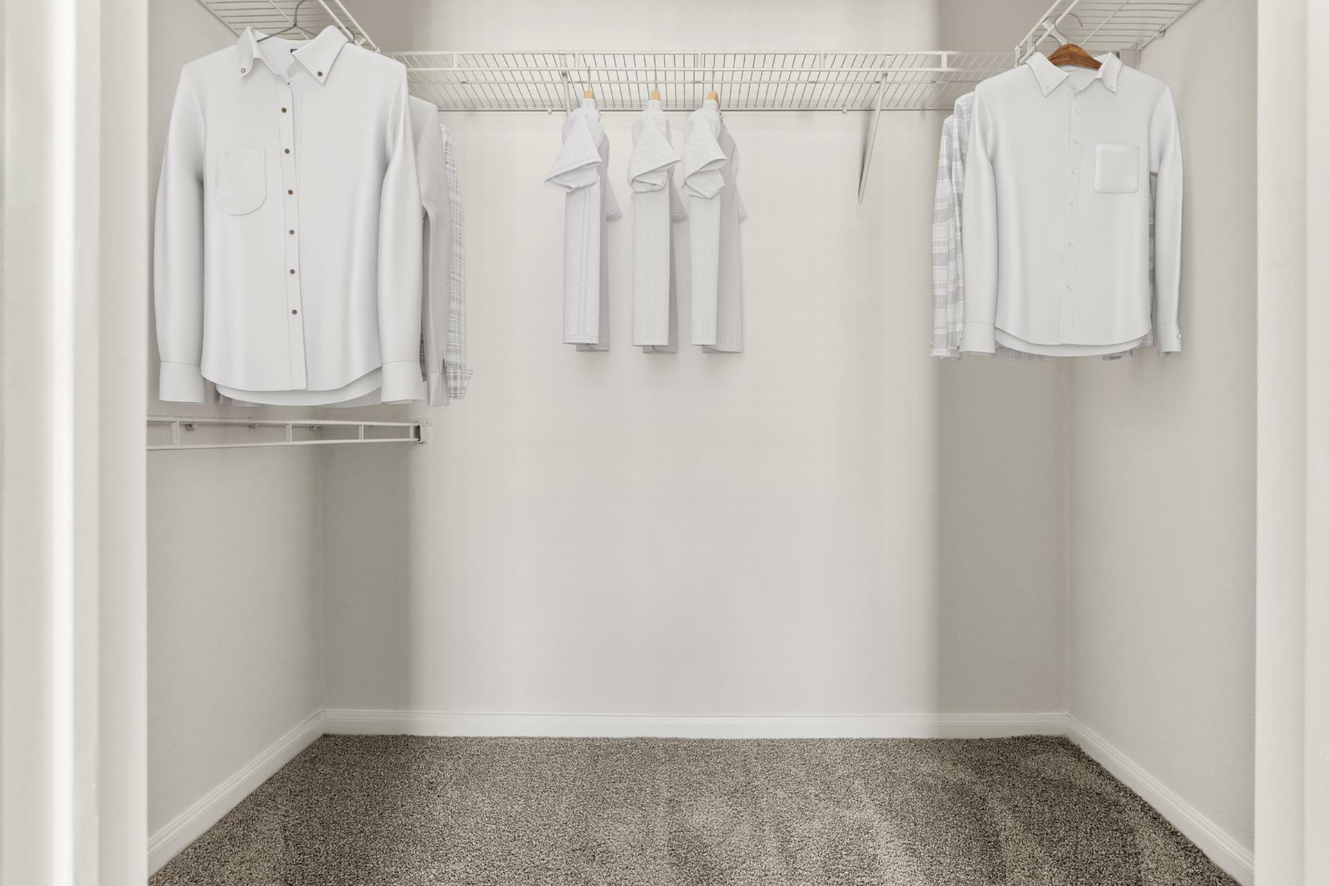 Spacious walk-in closet with pristine white shelving and neatly organized clothing, highlighting ample storage space.