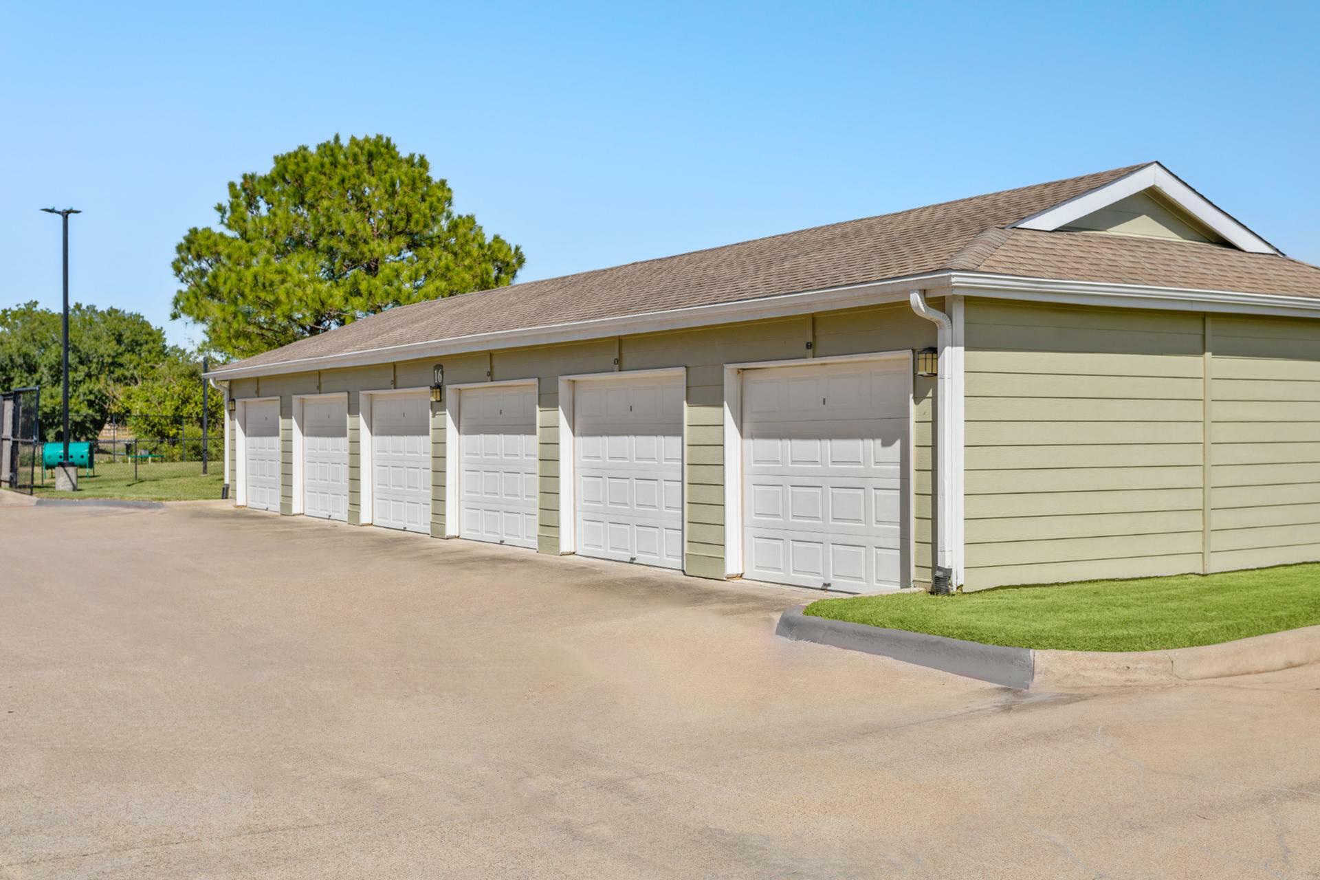 Expansive row of elegant, private garages with pristine white doors, set against a backdrop of lush greenery and clear blue skies.