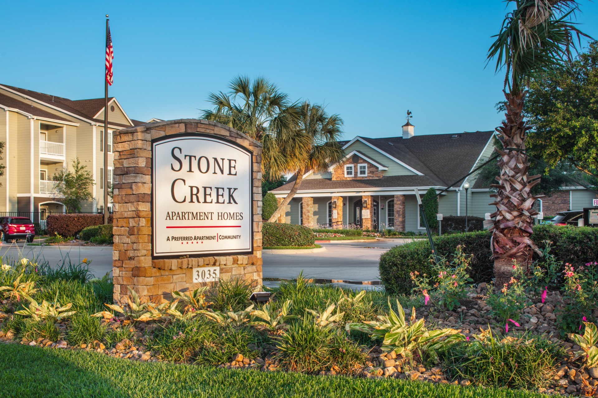 Charming Stone Creek Apartment Homes entrance with lush landscaping and rustic architecture welcoming you to a serene community.