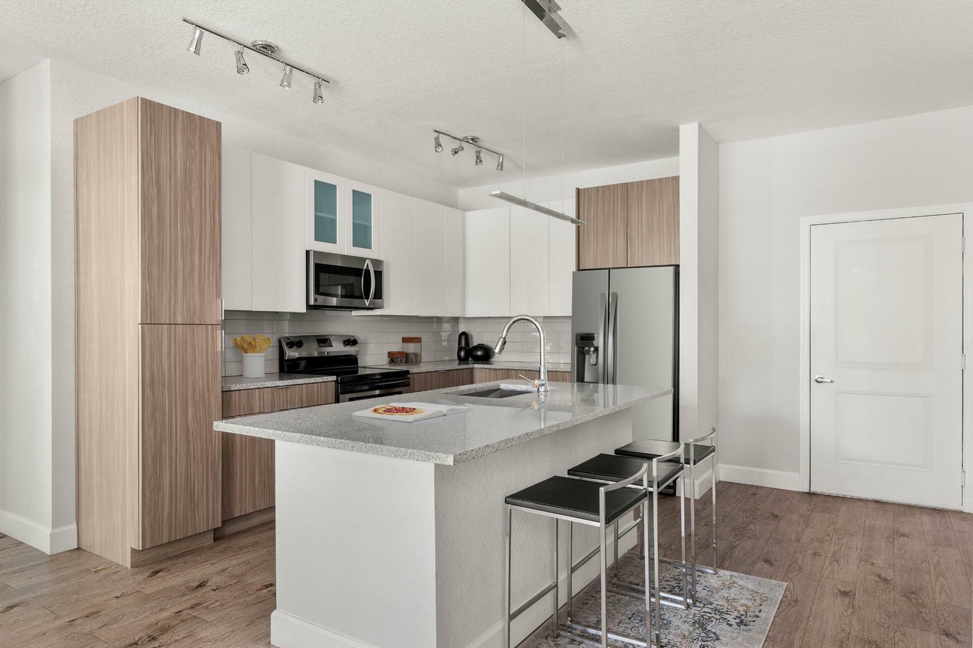 Modern kitchen with sleek design featuring an island, stainless steel appliances, and contemporary lighting.