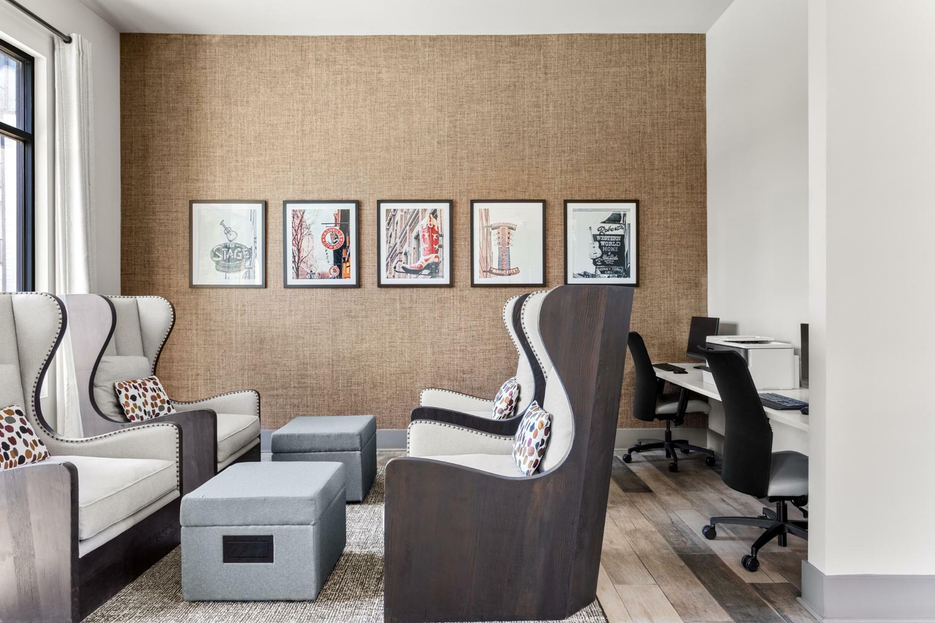 Chic apartment lounge featuring elegant high-back chairs, modern artwork, and a functional workspace with sleek computers.