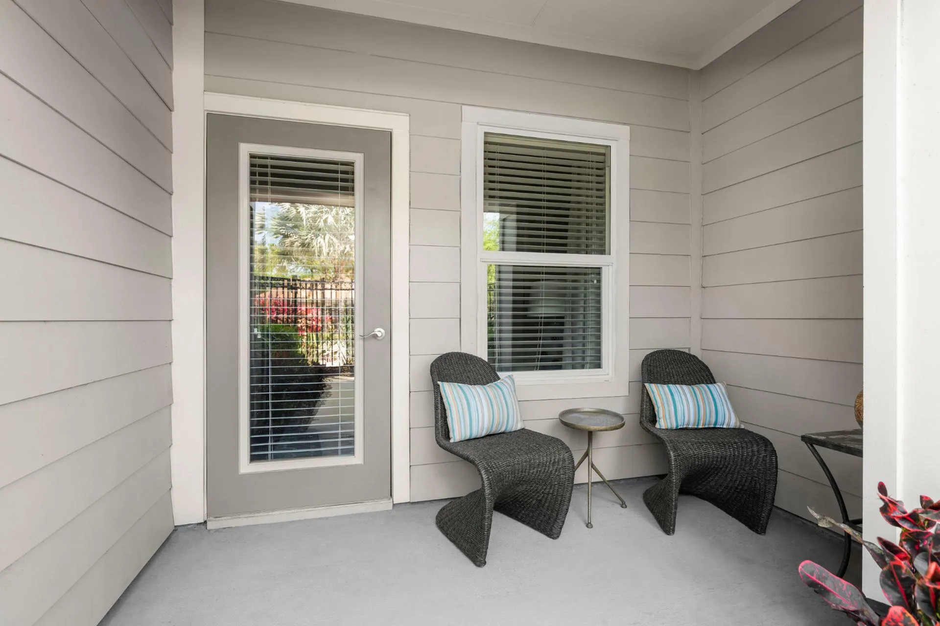 Charming patio space featuring modern wicker chairs and a chic side table, perfect for outdoor relaxation.