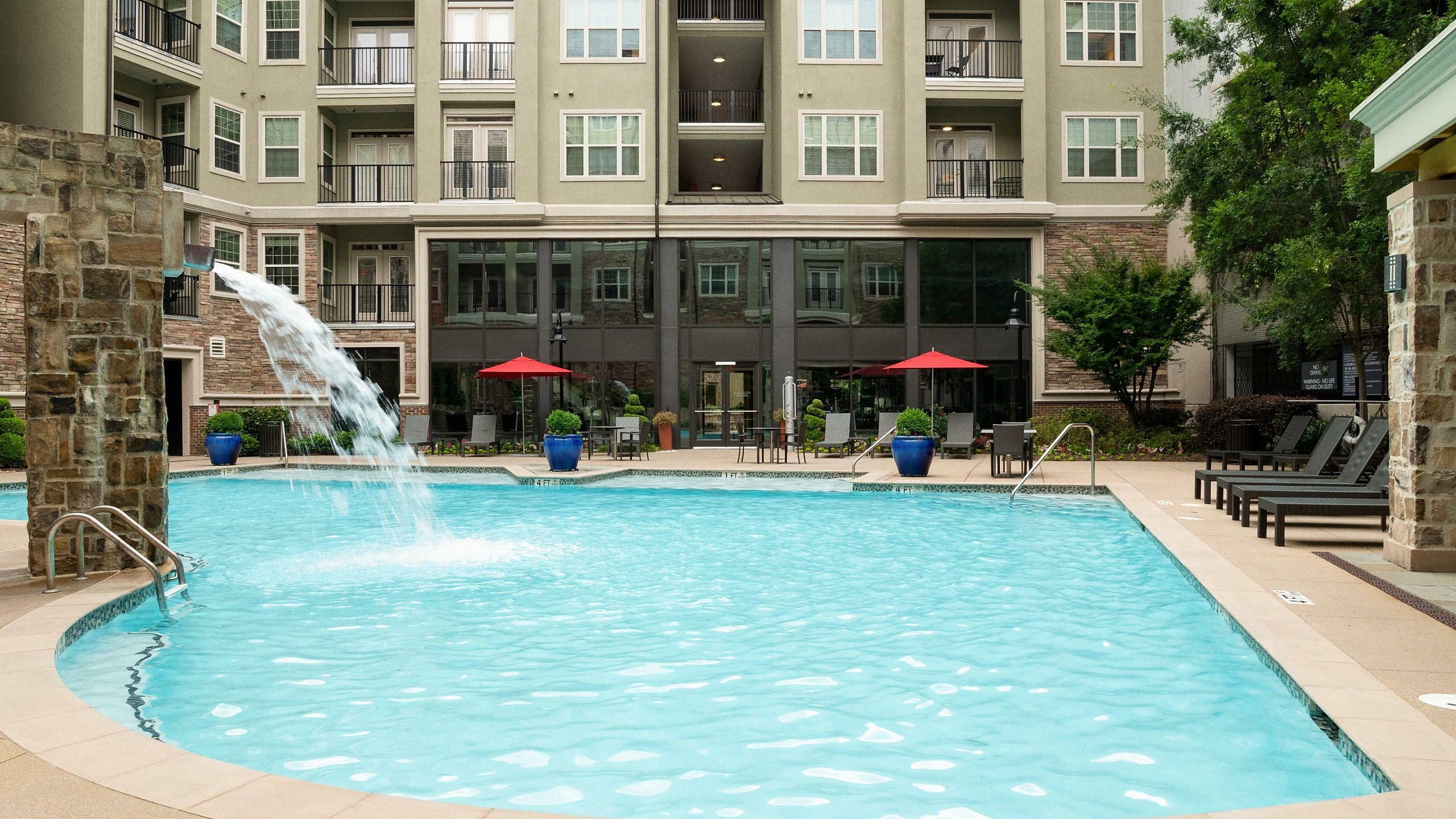 Inviting apartment pool area with waterfall feature and relaxing lounge chairs