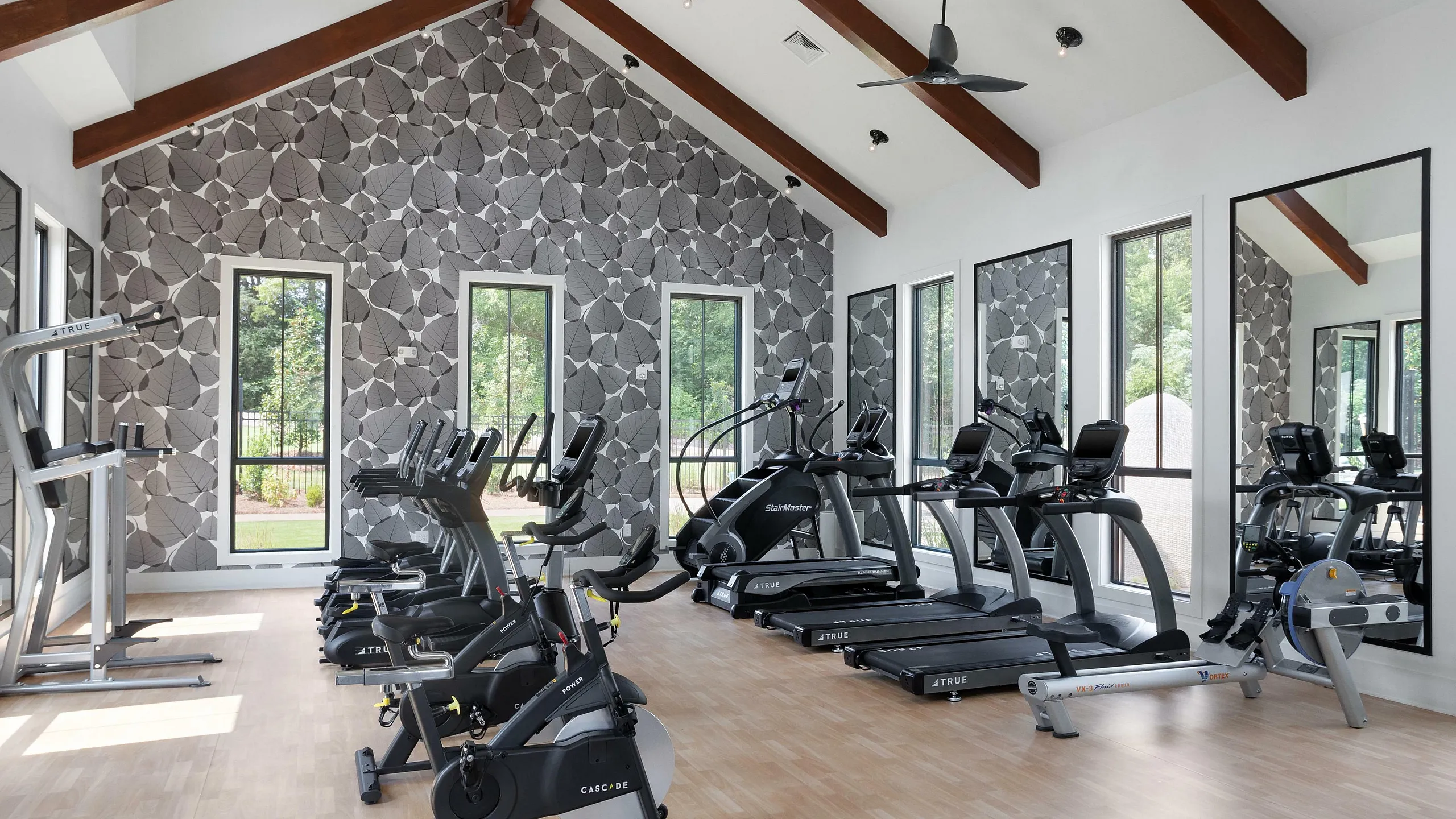 Bright and modern fitness center with state-of-the-art equipment and large windows overlooking a serene exterior.