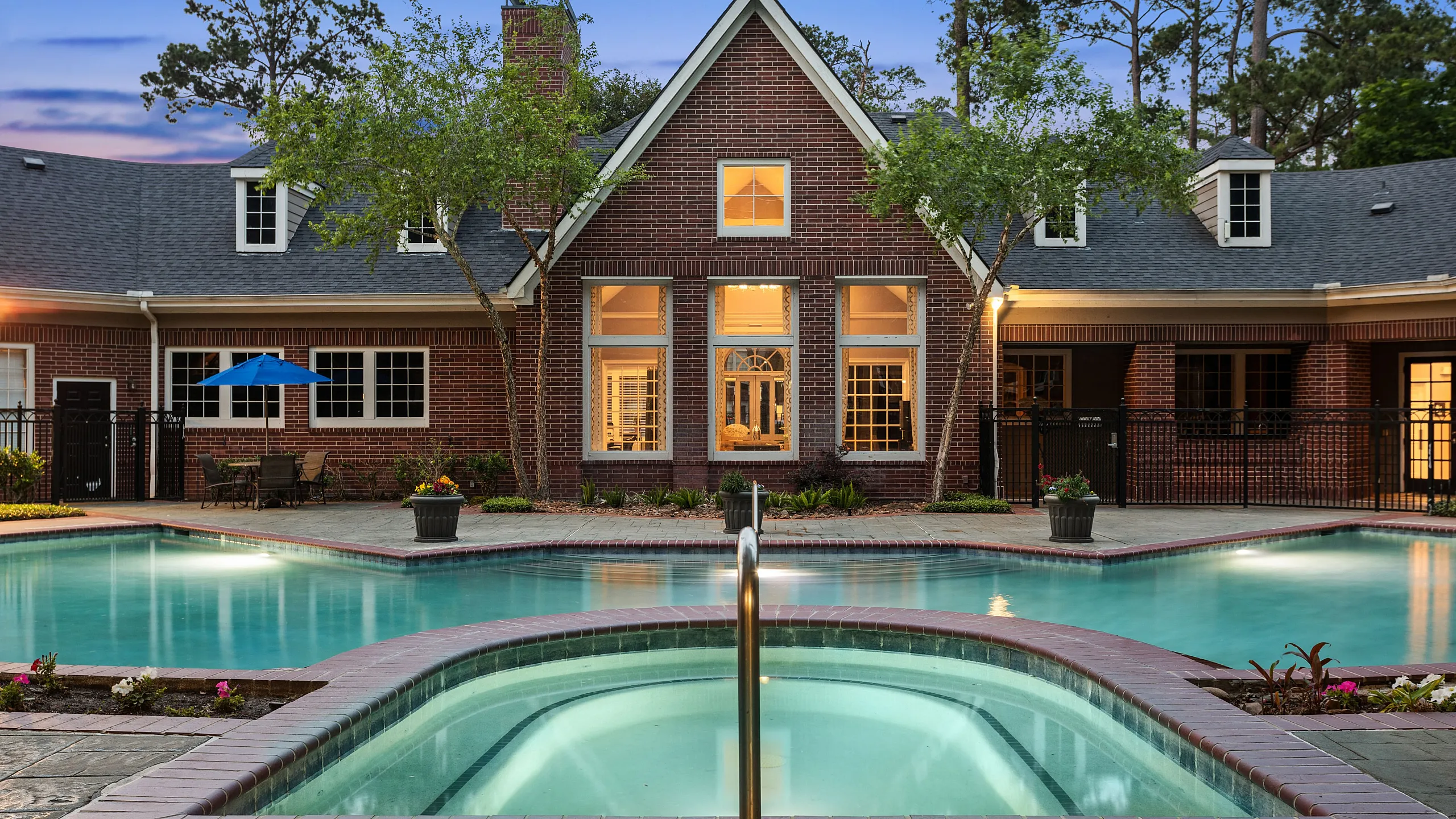 Charming brick residence with an inviting swimming pool and cozy outdoor seating, perfect for relaxation and entertaining.