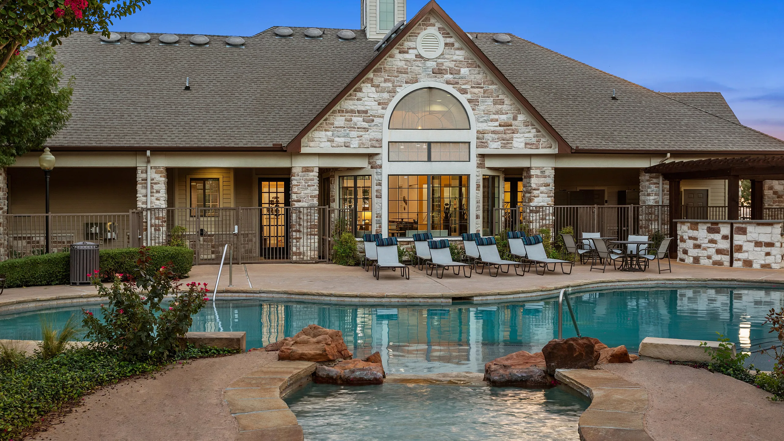 Charming apartment complex with inviting pool and stylish stone facade, offering a perfect blend of luxury and relaxation.