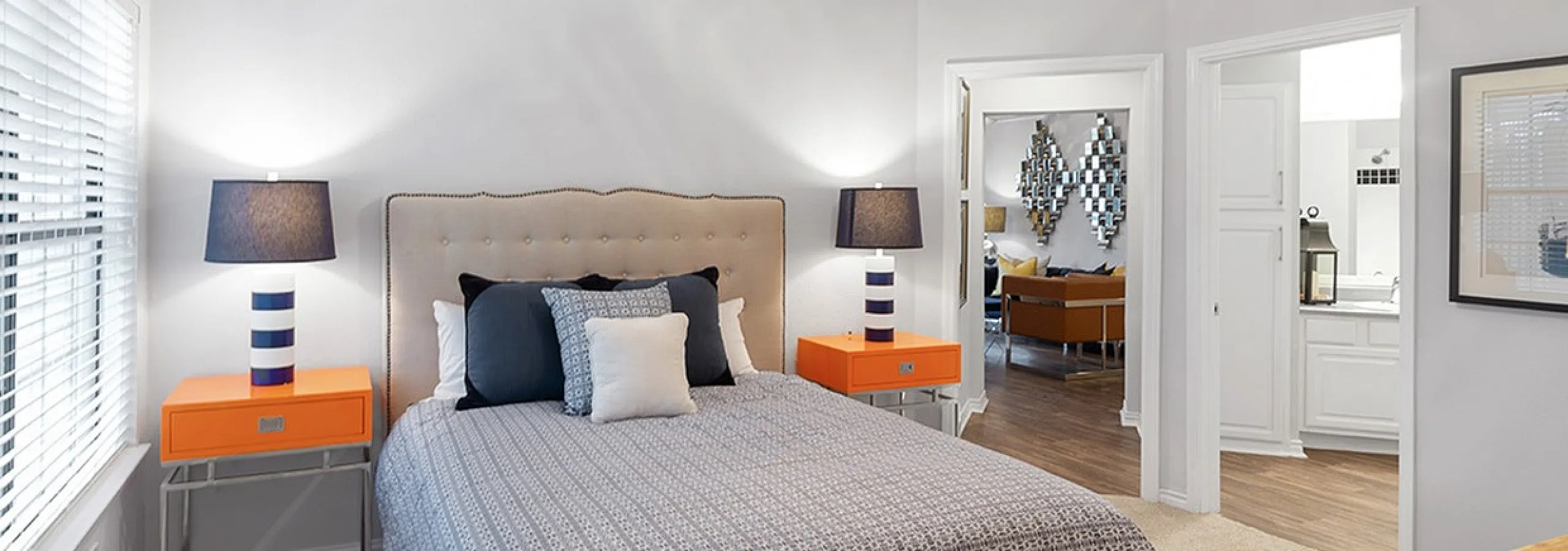 Bright and inviting bedroom with elegant decor, featuring a cozy bed, stylish orange bedside tables, and ample natural light.