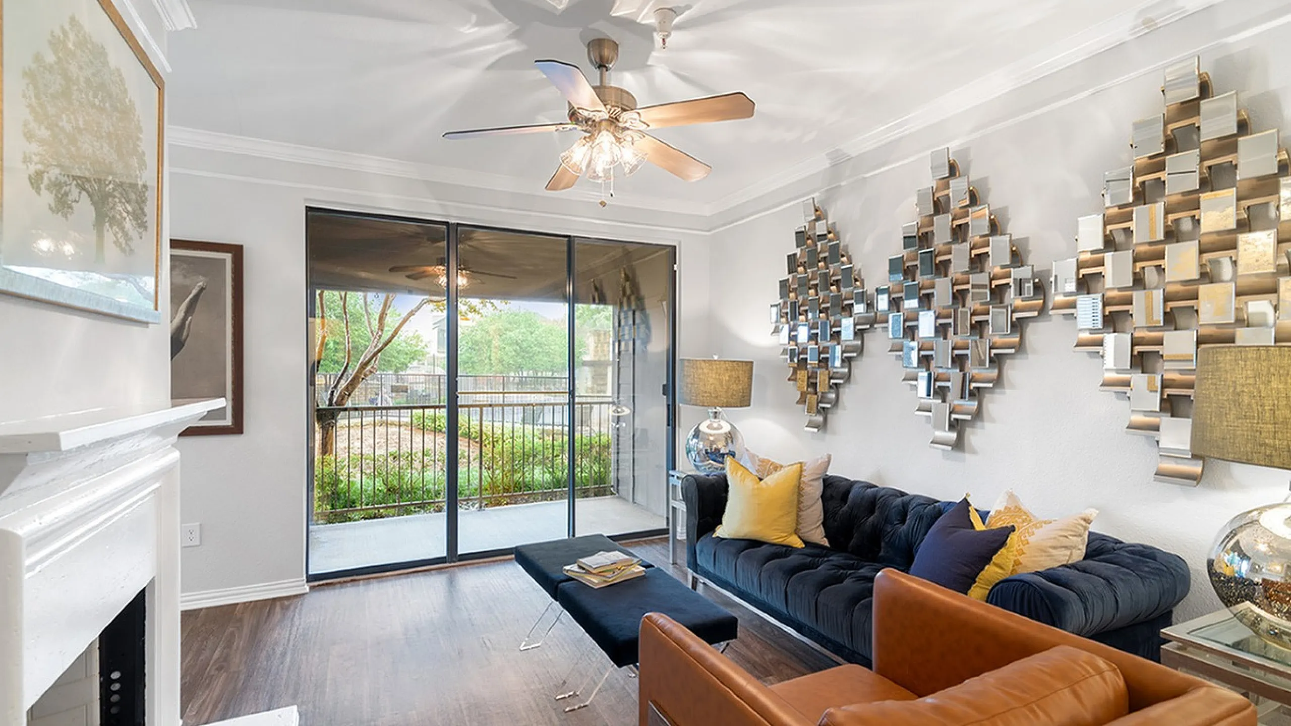 Bright and elegant living room with chic decor, featuring a plush navy sofa, modern art, and a view of the garden through large glass doors.