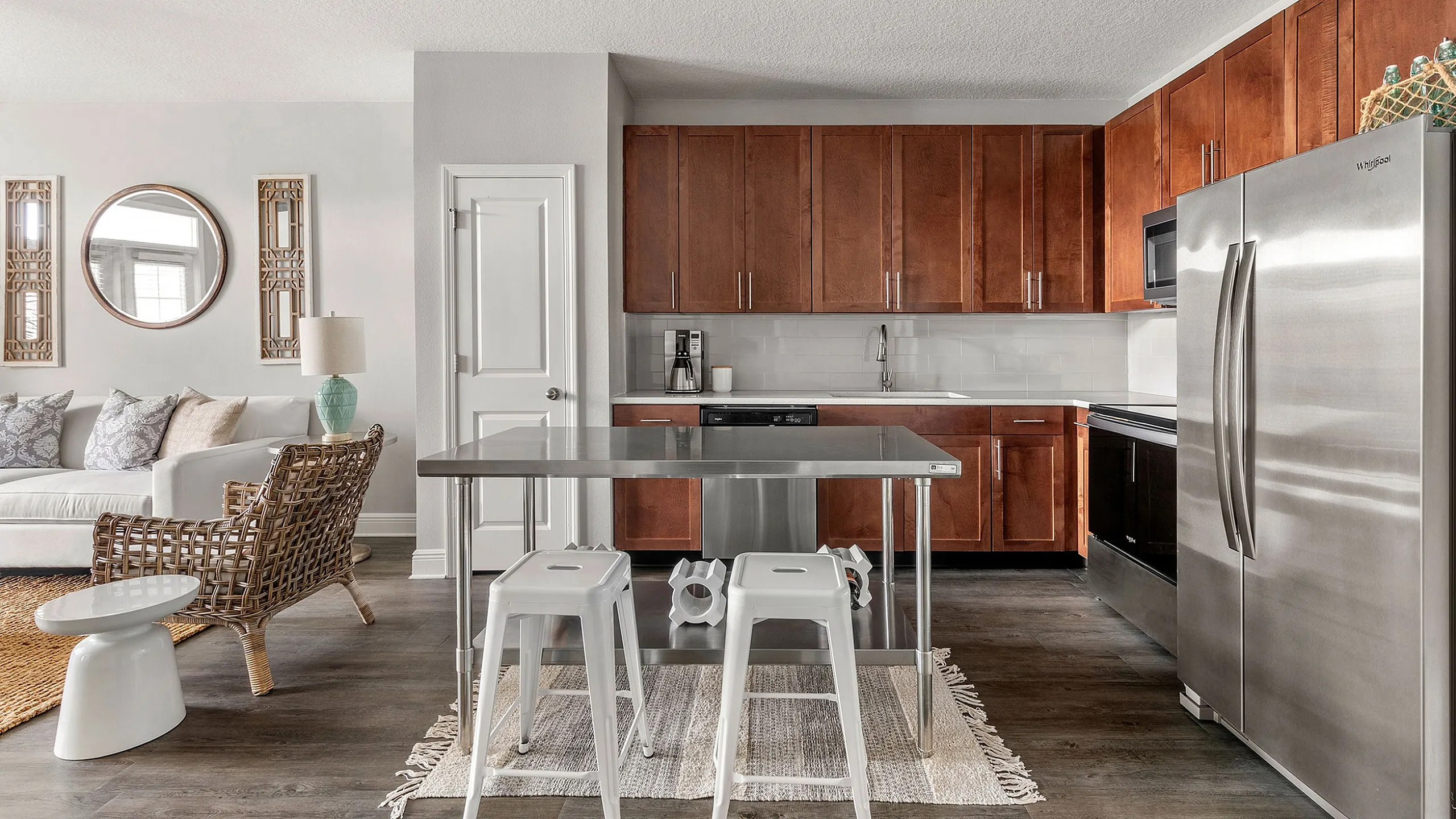 Modern open-concept kitchen with sleek stainless steel appliances, elegant dark wood cabinets, and cozy seating area in stylish apartment.