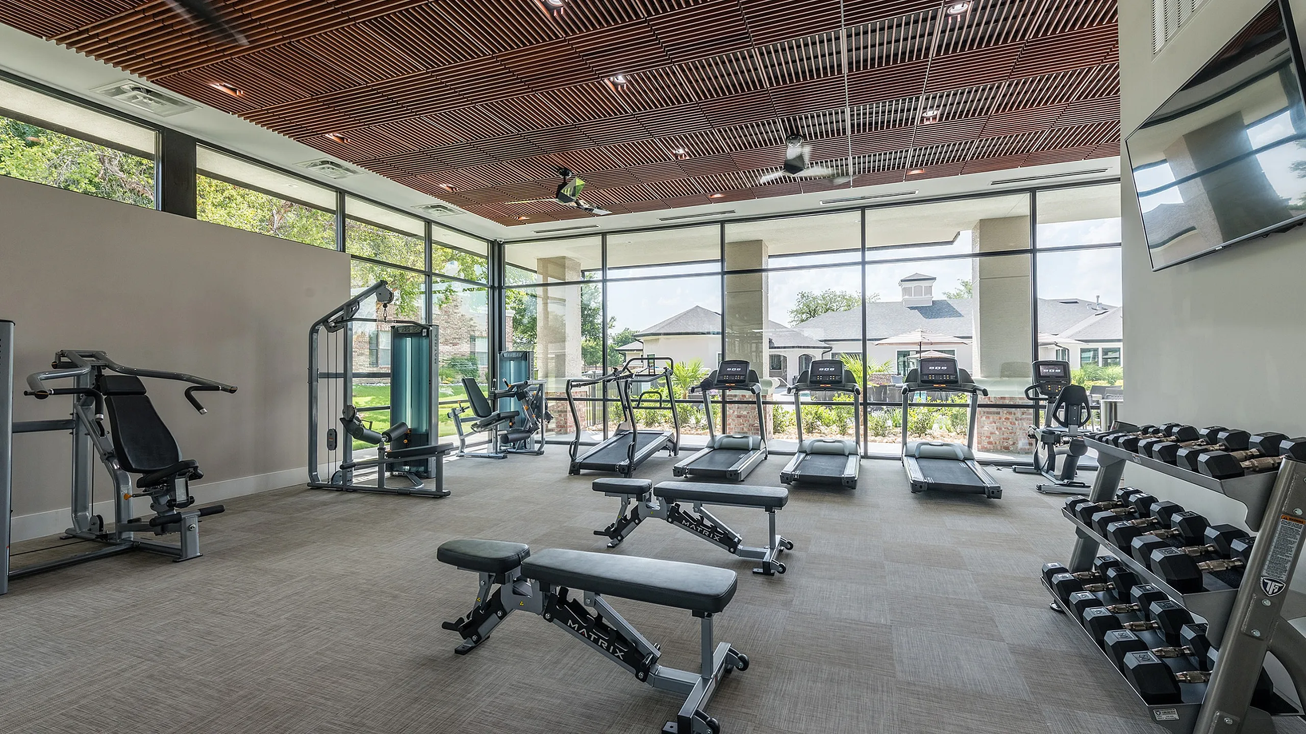 Modern apartment gym with state-of-the-art equipment, offering an inviting workout space with floor-to-ceiling windows and natural light.