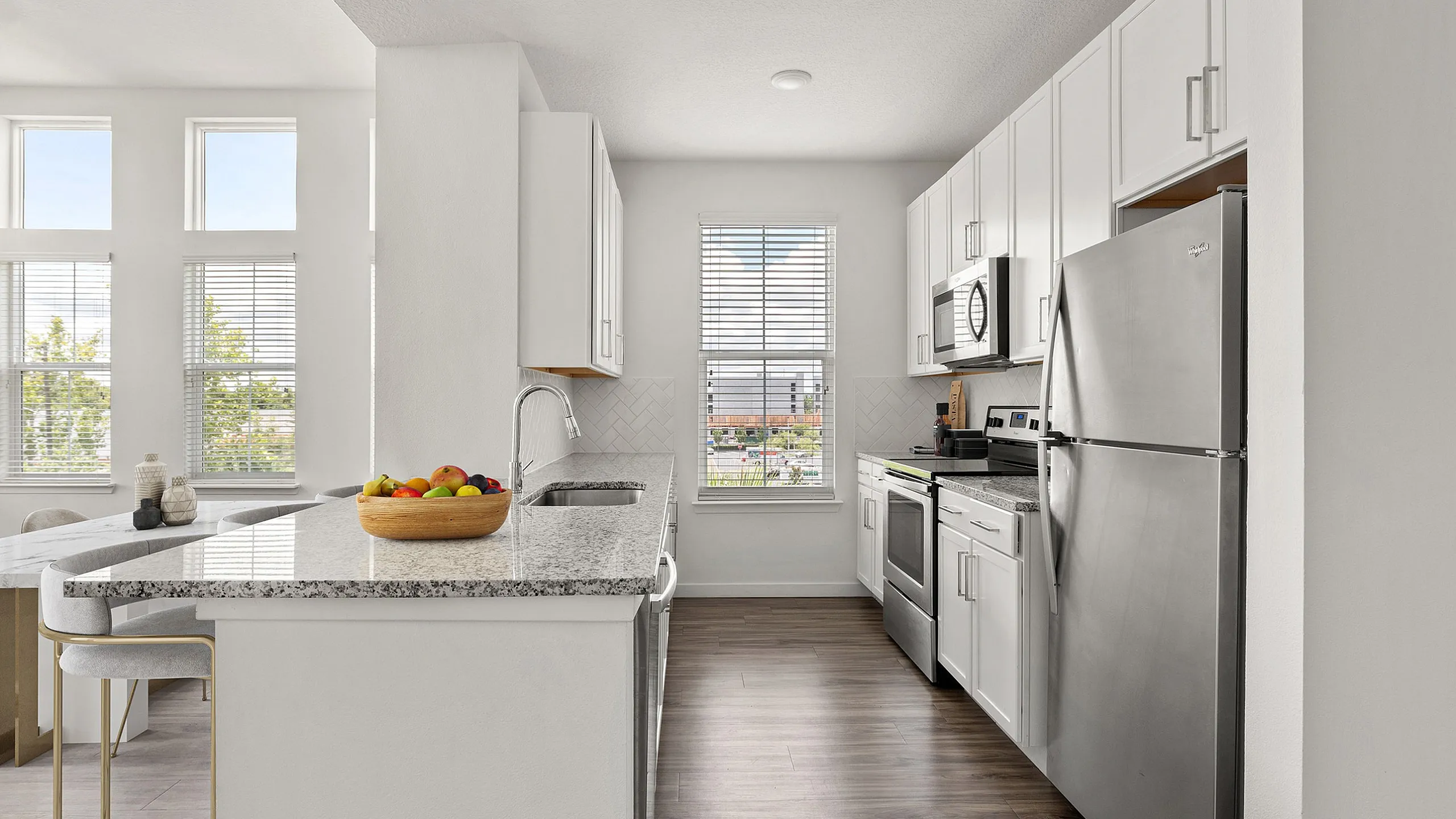 Bright modern kitchen with sleek stainless steel appliances, white cabinetry, and a granite countertop, perfect for culinary enthusiasts.