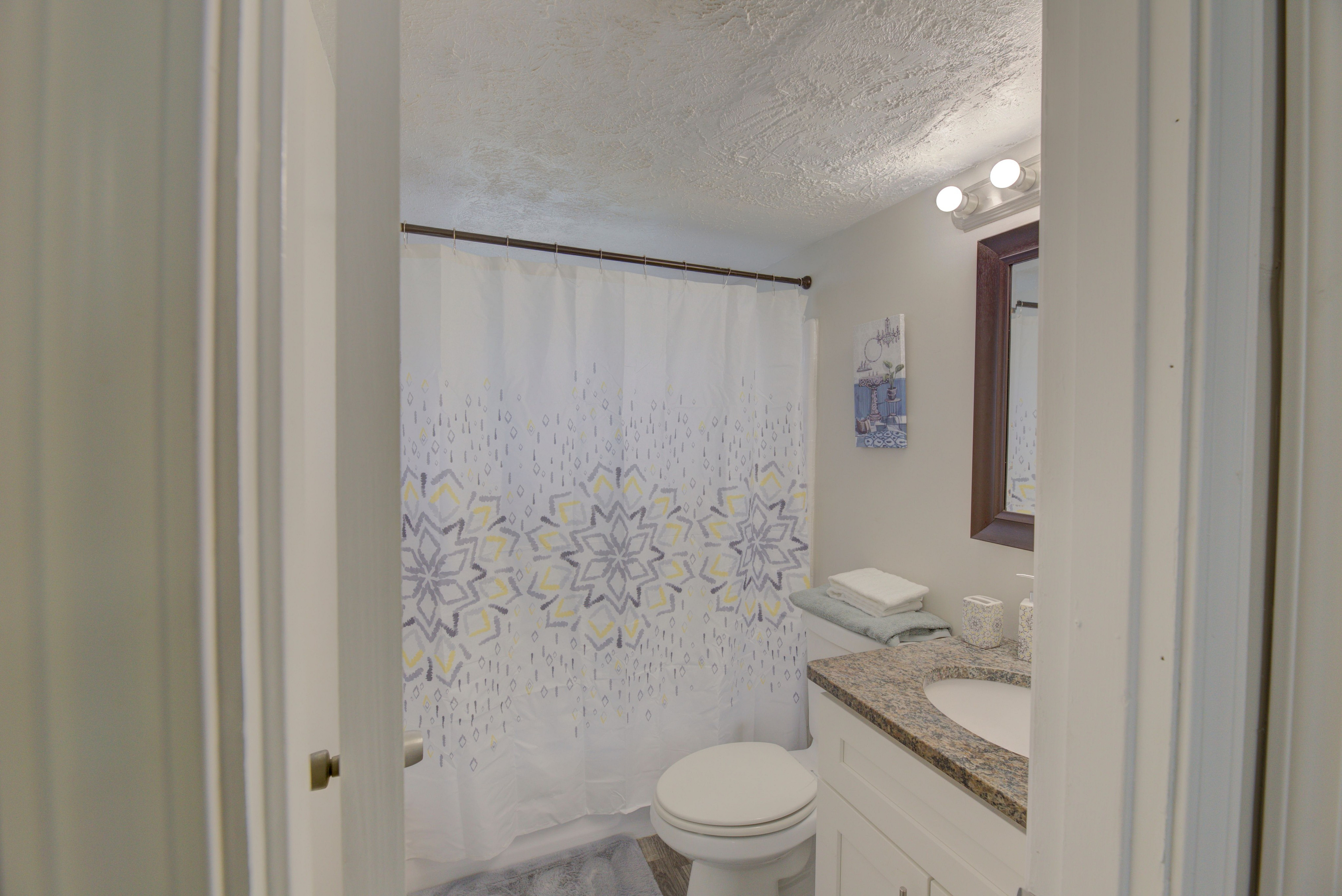 Charming bathroom with stylish patterned shower curtain, elegant granite vanity, and soft towels for a cozy, refreshing experience.