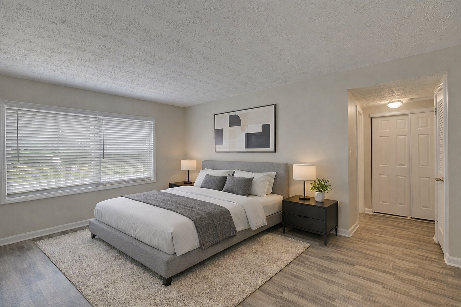 Elegant bedroom featuring a plush king-size bed, modern decor, and large windows for natural light.