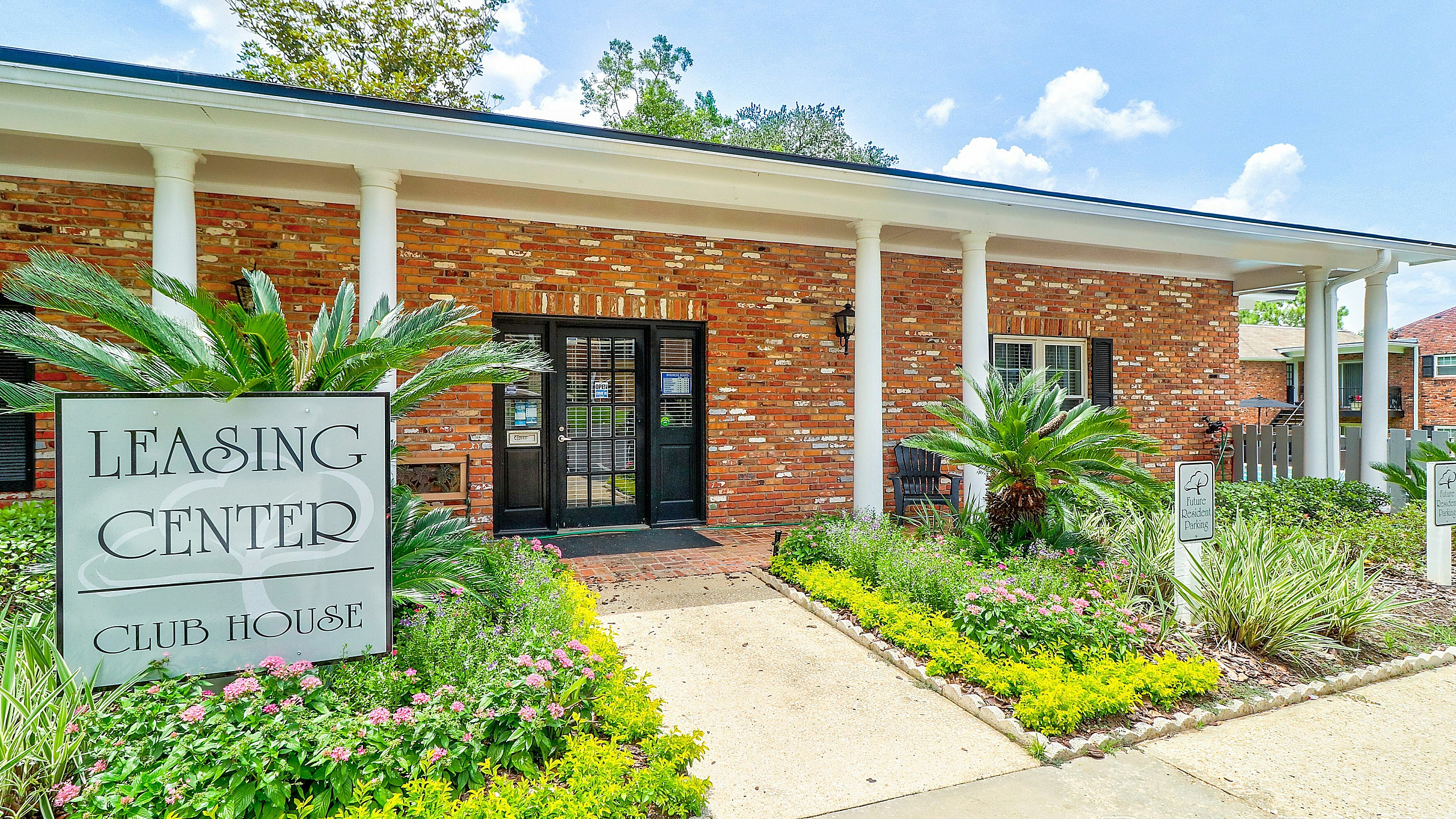 Inviting leasing center with charming brick exterior, lush landscaping, and welcoming entrance.