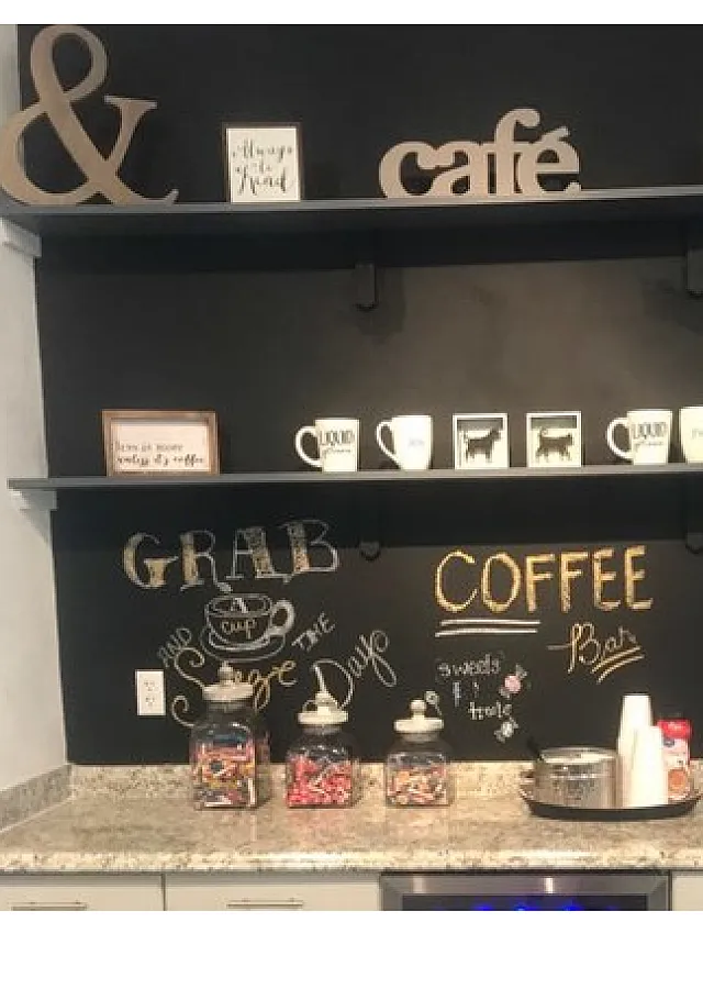 Charming caf&eacute;-themed kitchen nook with a stylish blackboard wall, inviting coffee station, and vibrant snack display.