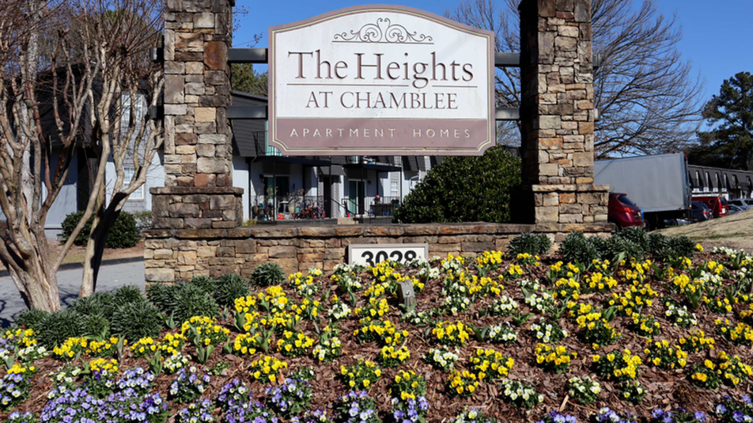 Welcoming entrance of The Heights at Chamblee apartment homes, featuring beautiful landscaped flowers and a charming stone sign.