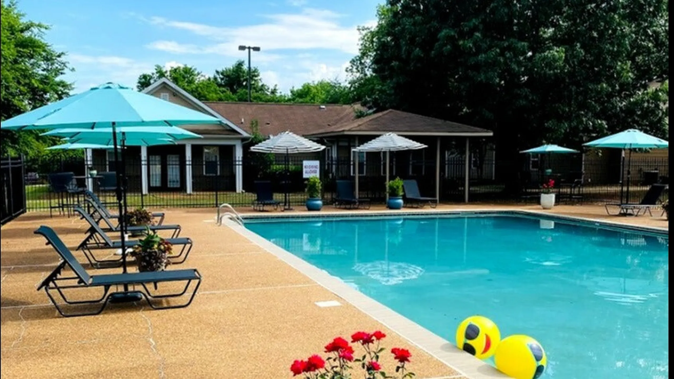 Inviting outdoor pool area with vibrant flowers, comfy loungers, and chic umbrellas, perfect for relaxation and leisure.