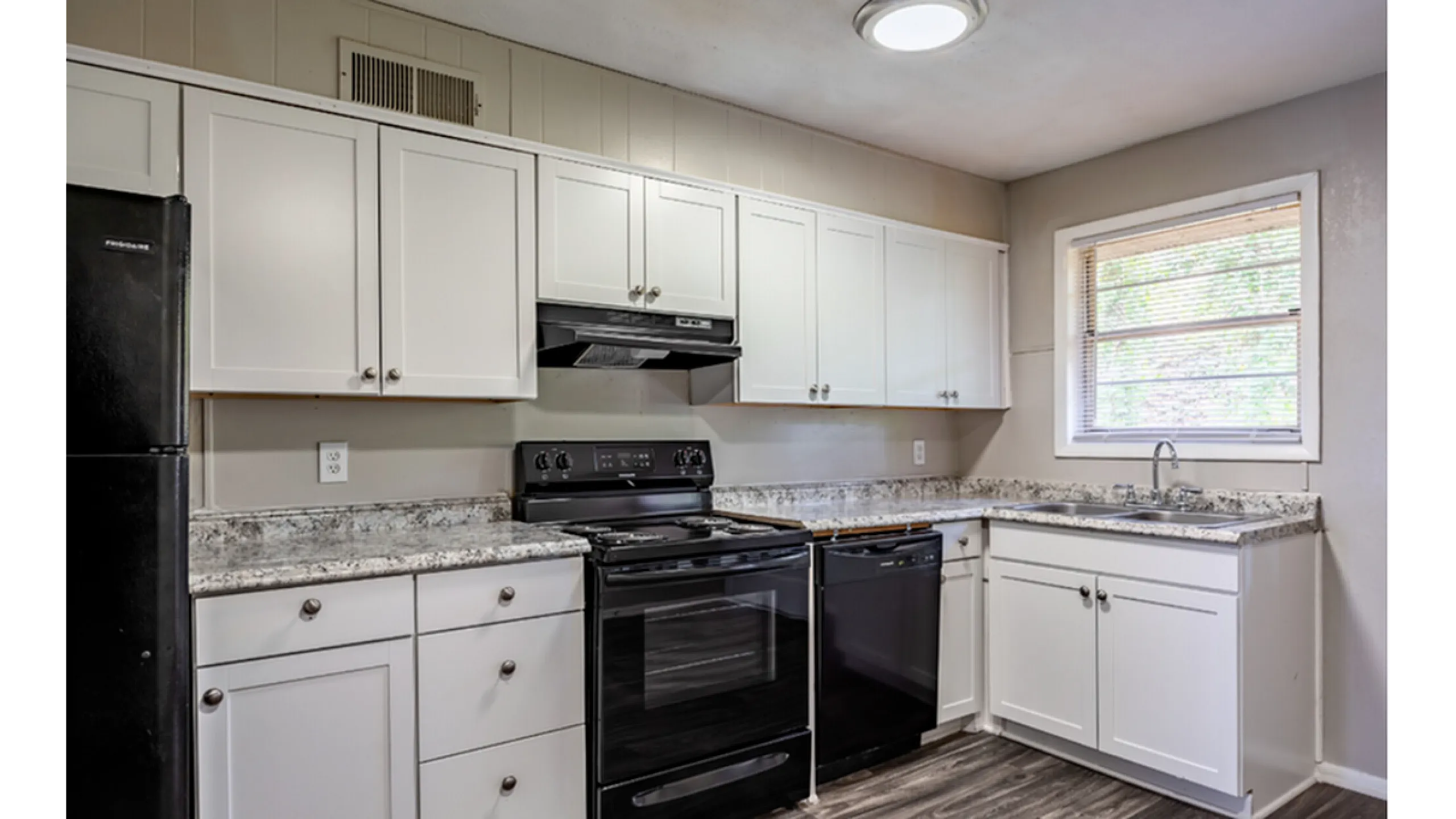 Modern kitchen with sleek black appliances, elegant white cabinetry, and stylish granite countertops.