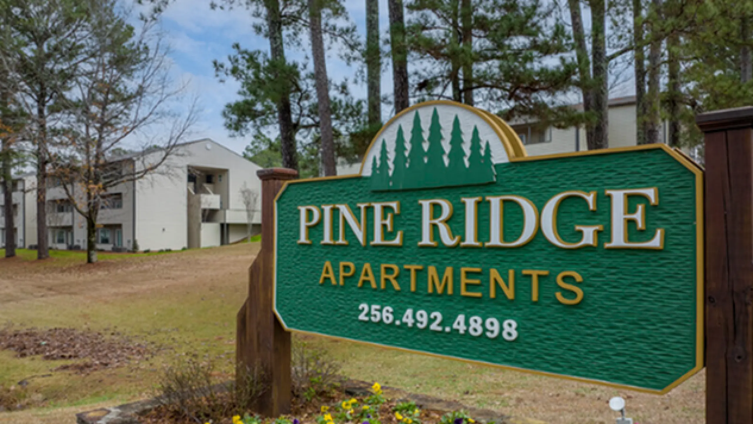 Inviting entrance to Pine Ridge Apartments surrounded by lush greenery, showcasing a tranquil and welcoming environment.