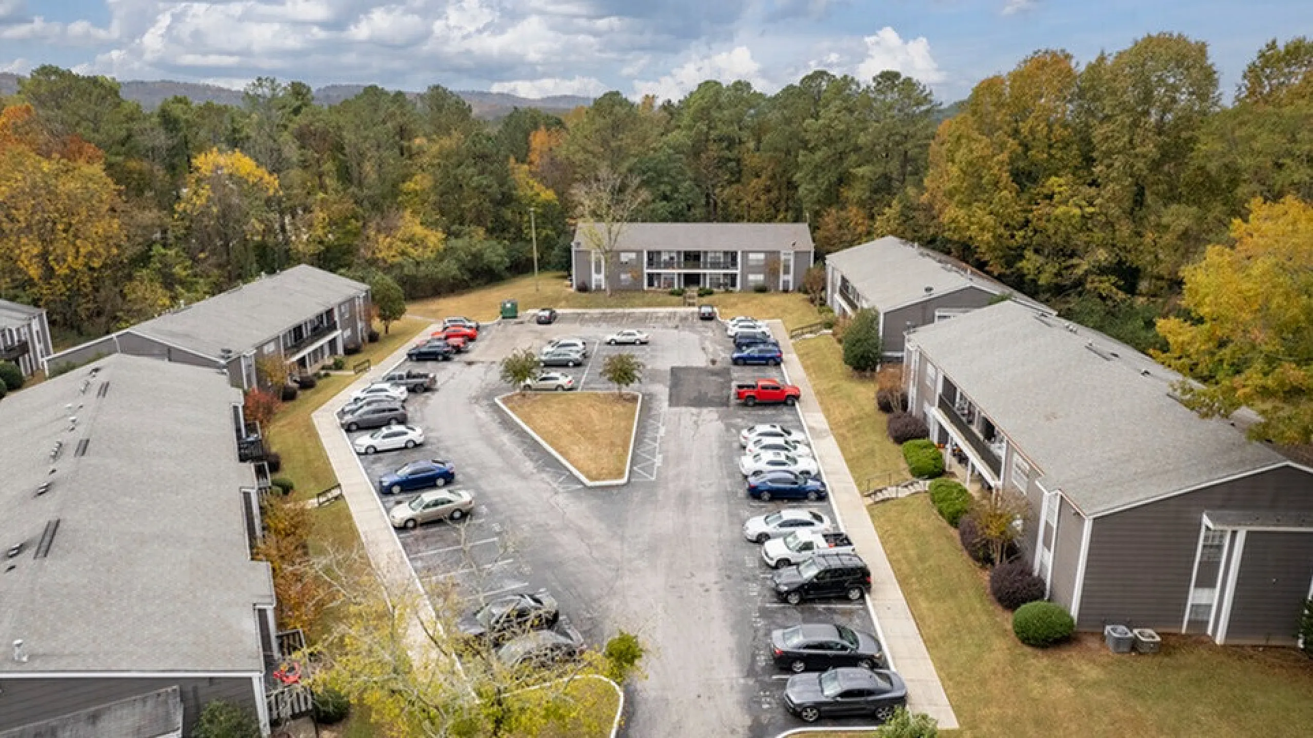 Charming apartment community with landscaped surroundings, ample parking, and lush green views, perfect for serene living.