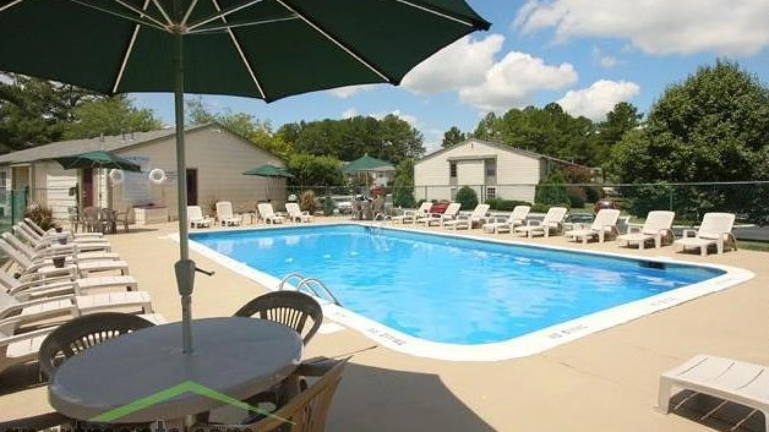 Inviting outdoor pool area with plenty of lounge chairs and shaded tables, perfect for relaxation on a sunny day.