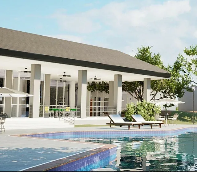 Luxurious outdoor pool area featuring sleek lounge chairs, vibrant landscaping, and a modern clubhouse under clear blue skies.