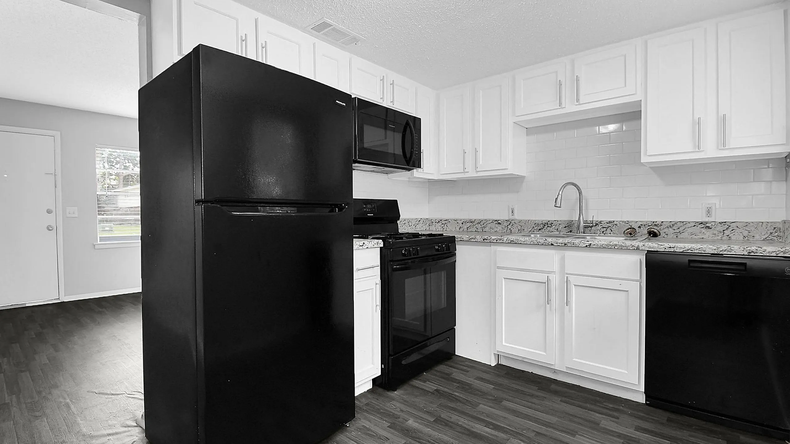 Modern kitchen featuring sleek black appliances, elegant granite countertops, and bright white cabinetry, creating an inviting cooking space.