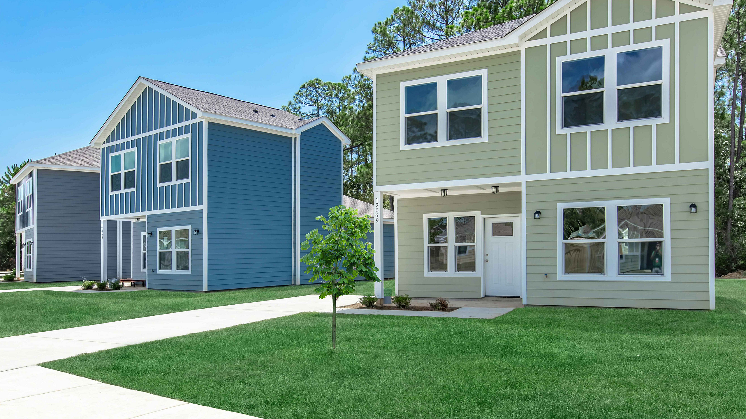 Charming modern homes with bright facades and lush green lawns, nestled in a peaceful neighborhood.
