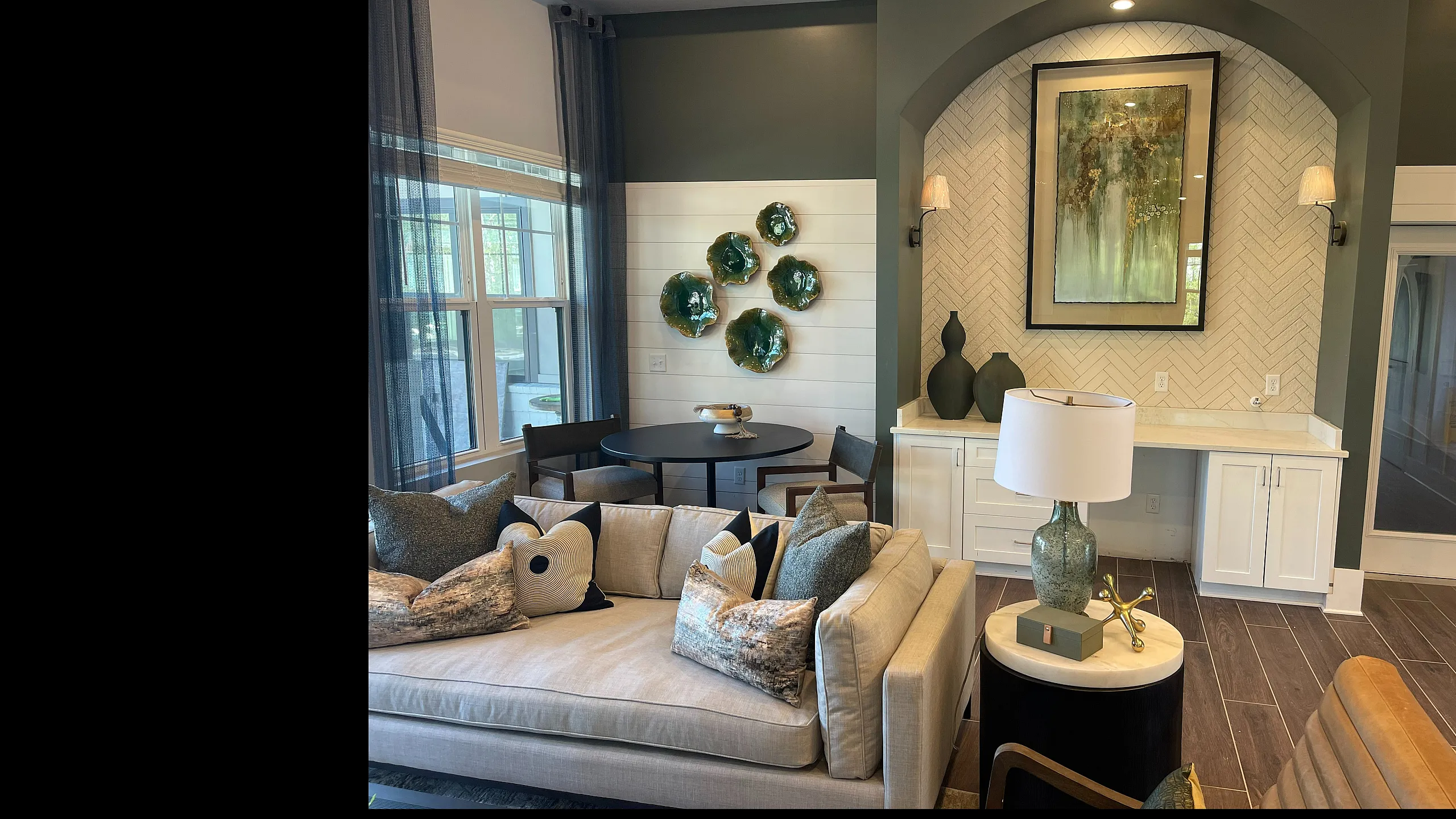 Elegant living room with stylish decor, featuring a plush sofa, artistic wall accents, and large windows for natural light.