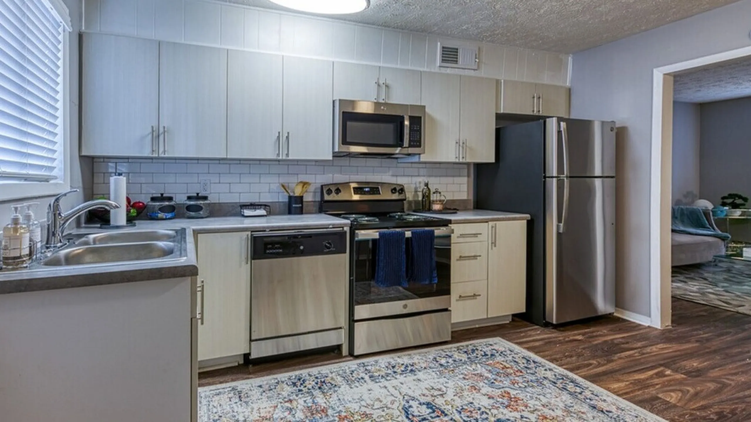 Modern kitchen with stainless steel appliances, elegant cabinets, and a cozy, textured carpet.