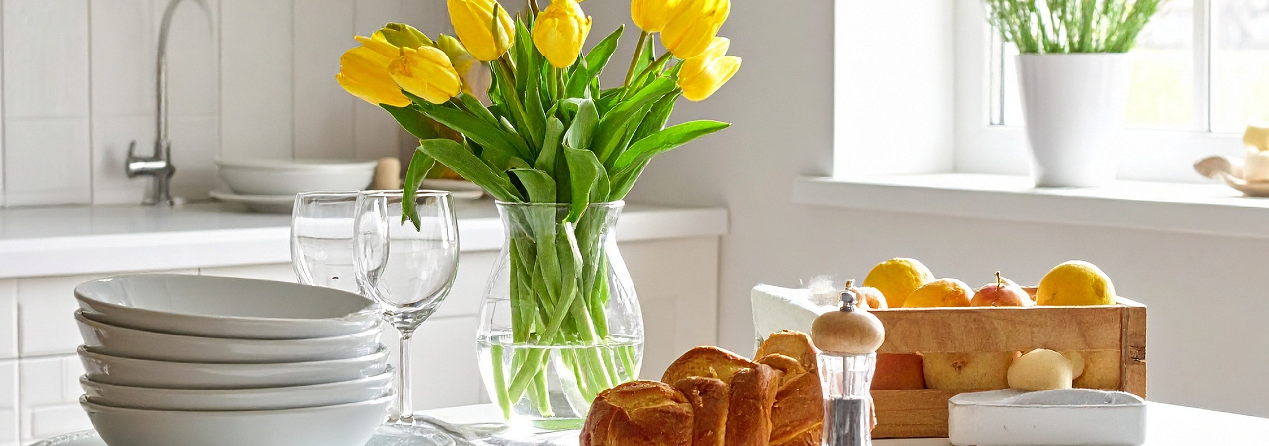 Bright and inviting kitchen with sunny yellow tulips, fresh fruit, and elegant table setting.