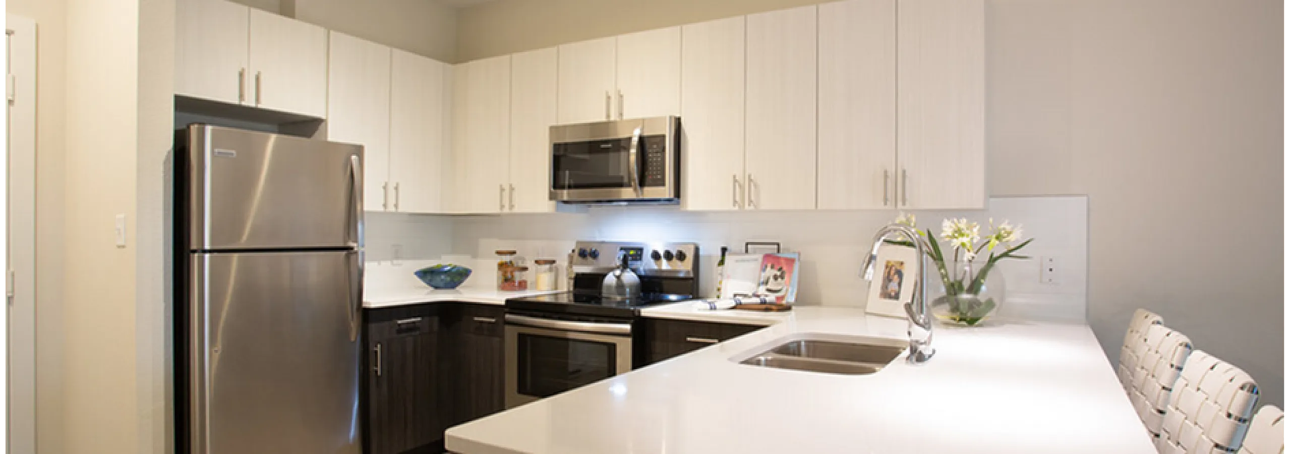 Modern kitchen with sleek stainless steel appliances, elegant white cabinetry, and a stylish breakfast bar adorned with chic bar stools.