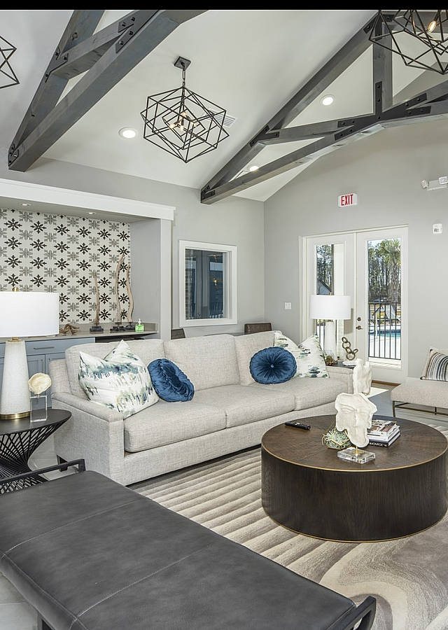Modern living room with elegant decor, featuring a stylish gray sofa, contemporary lighting, and a view of the pool through large glass doors.