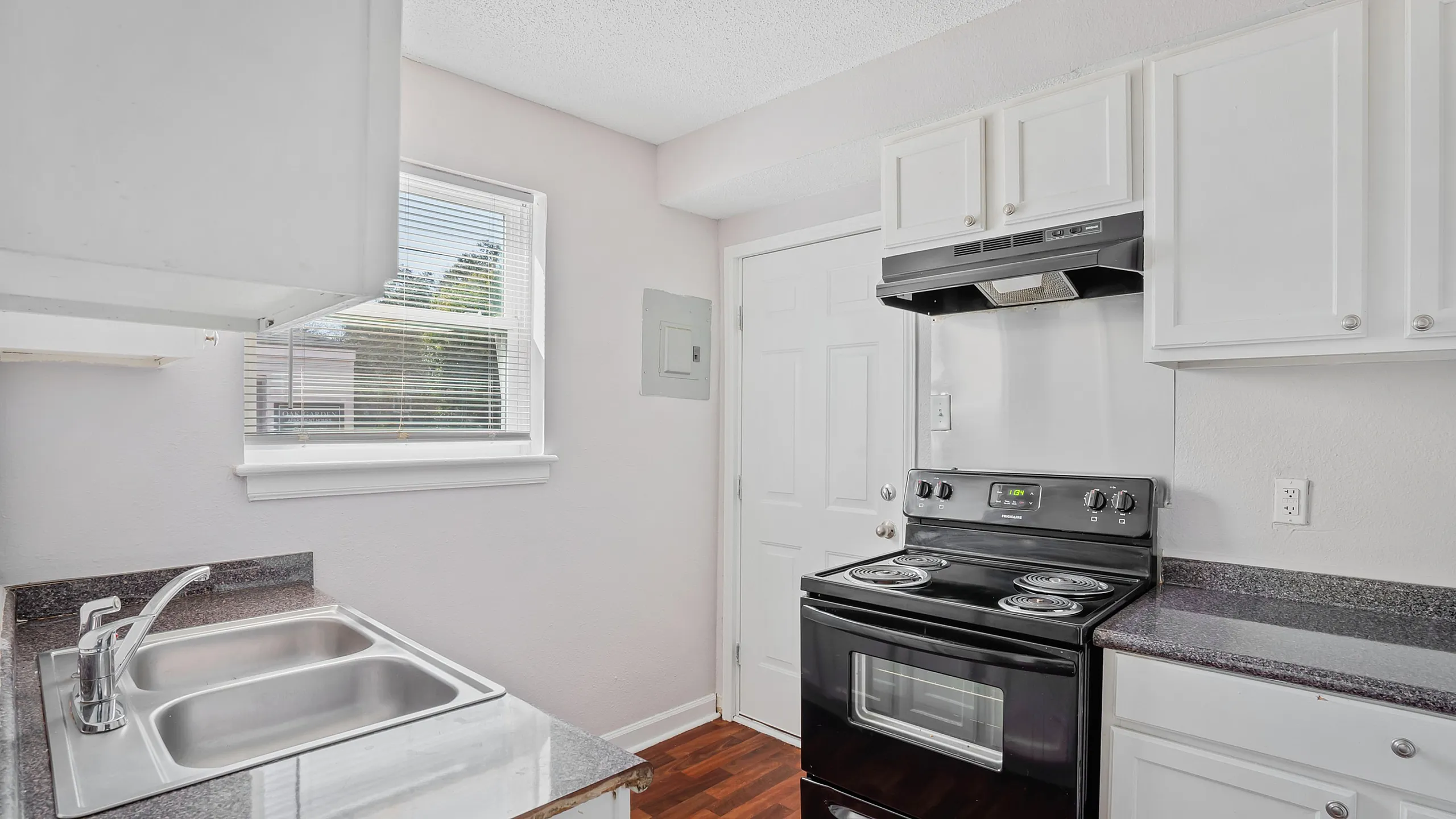 Bright kitchen with modern black appliances, granite countertops, and ample white cabinetry. Sunlit window creates a welcoming atmosphere.