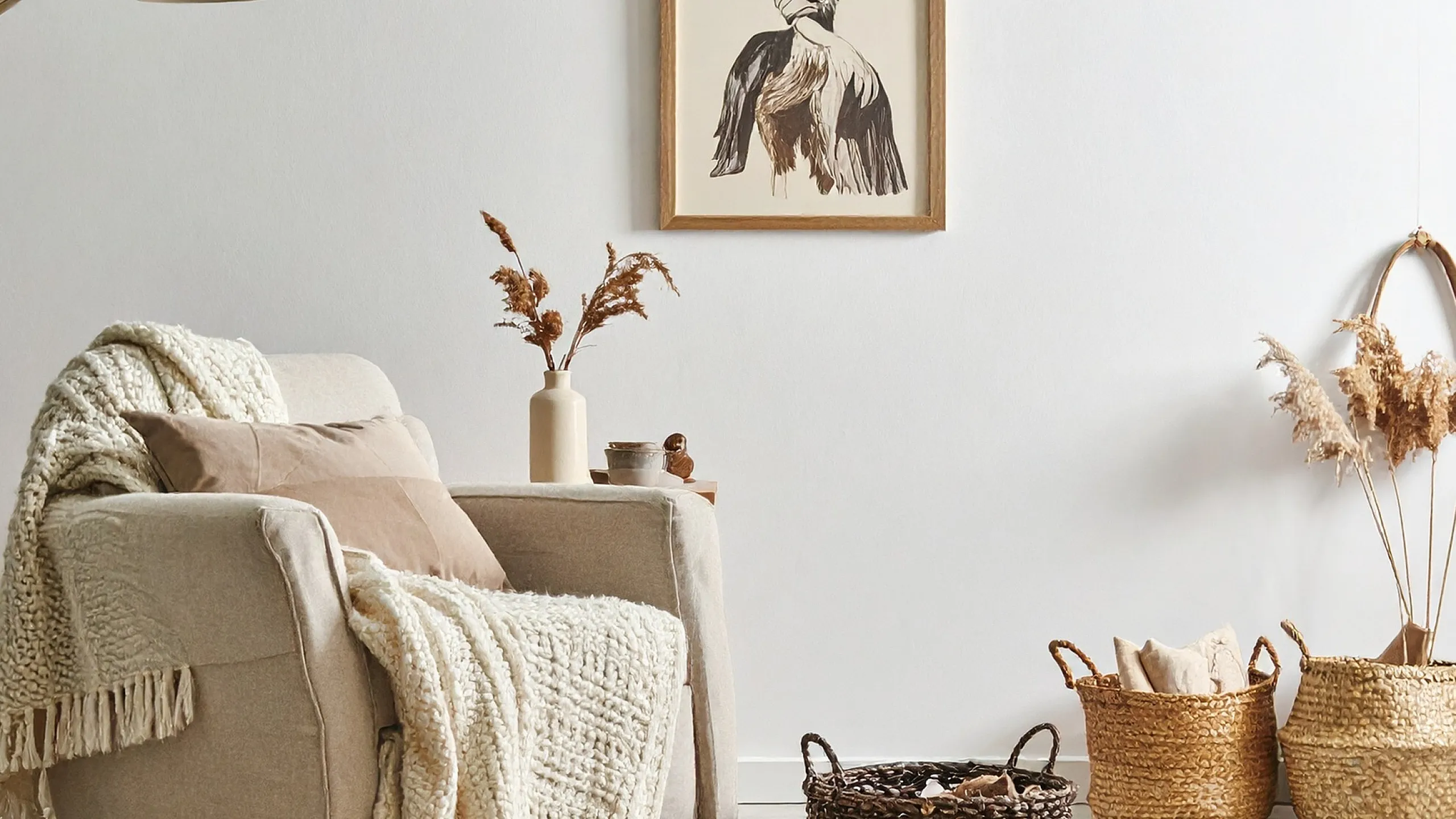 Cozy living room corner with a plush armchair adorned with a soft knitted throw, surrounded by stylish woven baskets and warm decor accents.