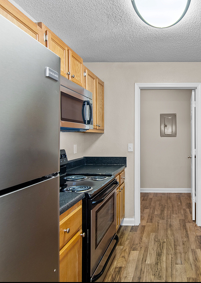 Modern kitchen with stainless steel appliances, sleek countertops, and warm wooden cabinetry.