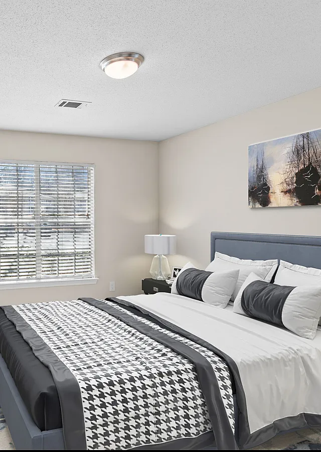 Inviting bedroom with cozy bedding, elegant artwork, natural light through a large window, and lush greenery for a tranquil atmosphere.