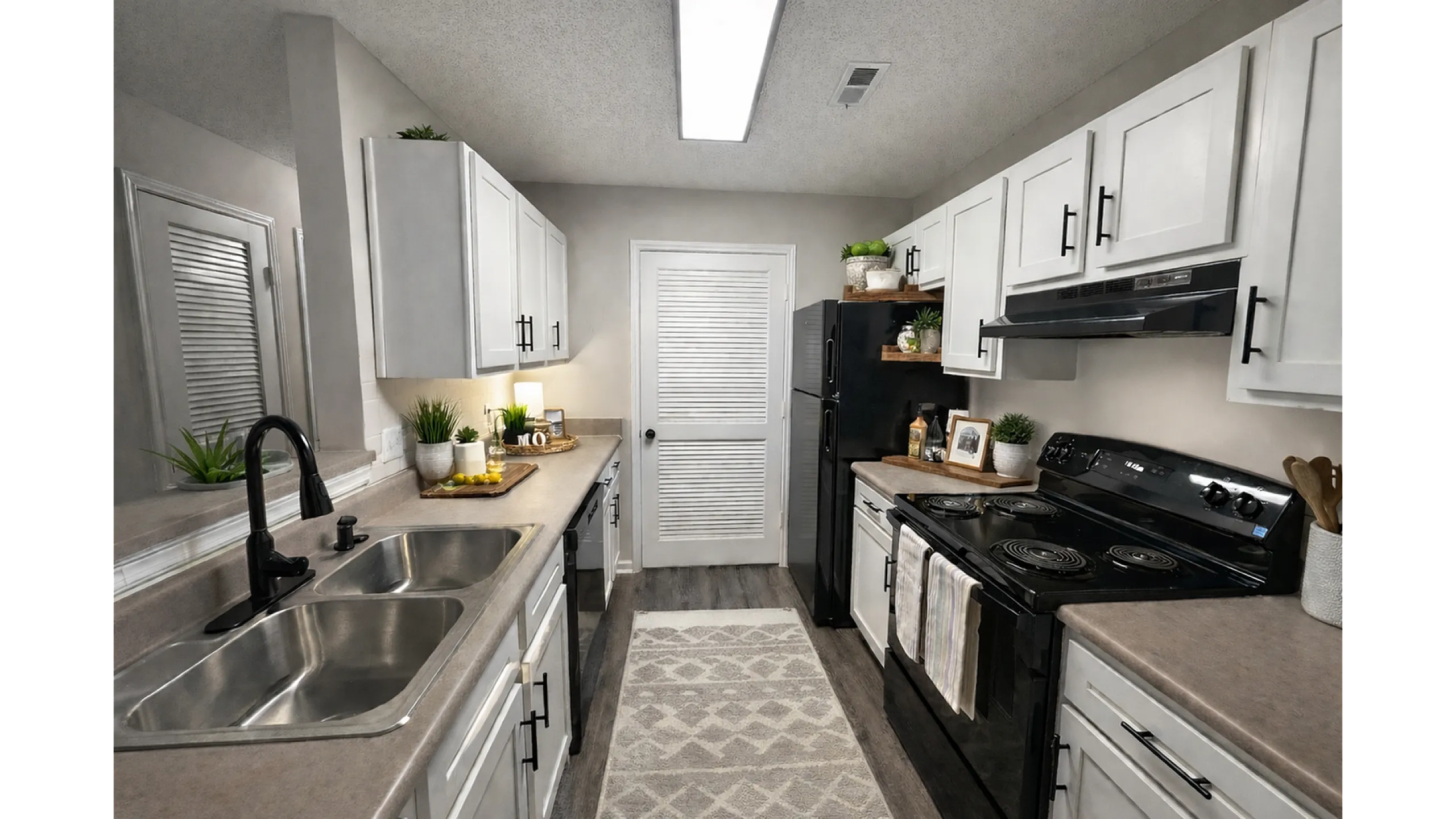 Contemporary kitchen with sleek black appliances, stylish white cabinetry, and elegant countertop decor.