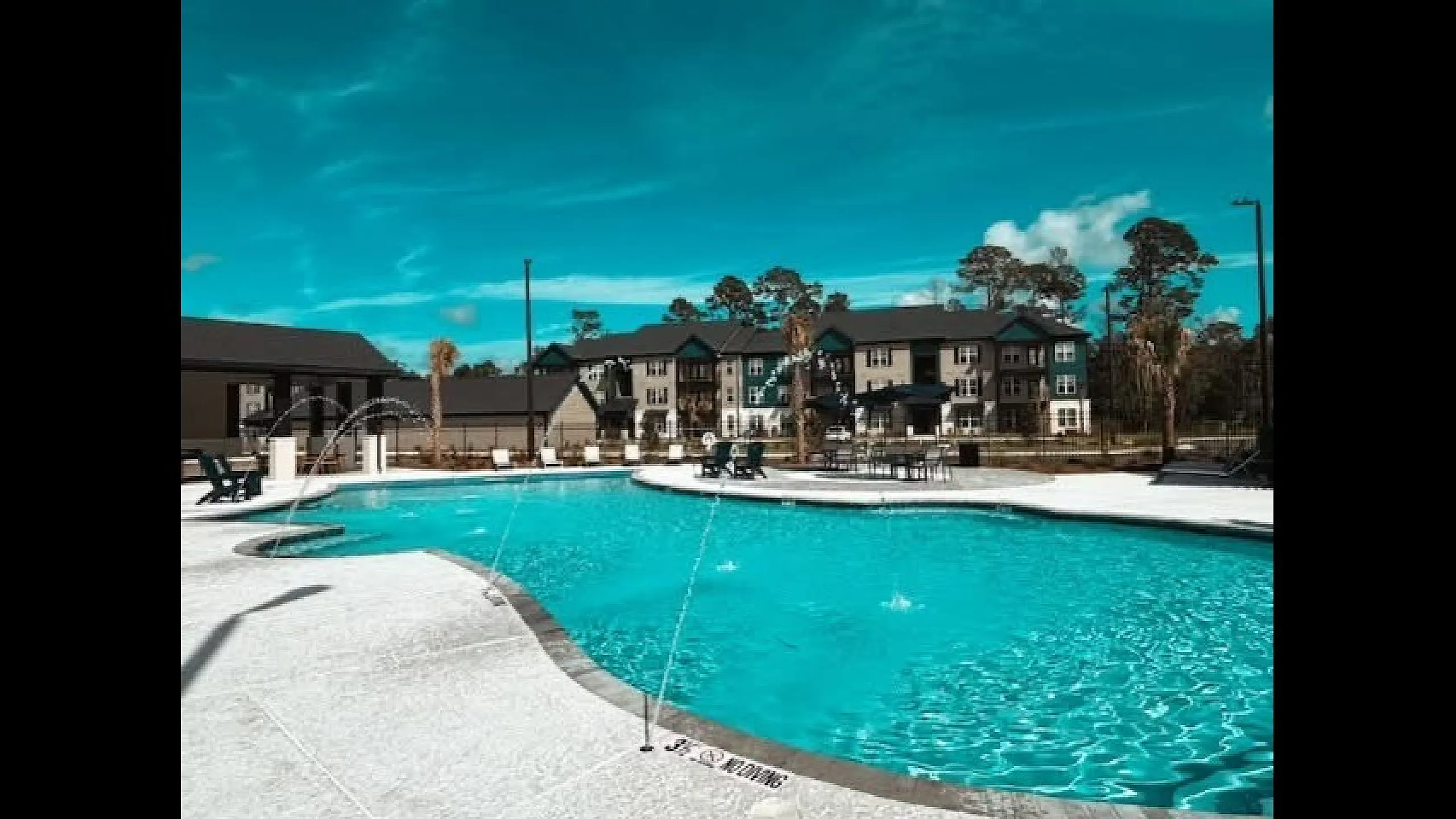 Inviting apartment complex with luxurious pool, surrounded by lush greenery and modern architecture, perfect for relaxation and leisure.