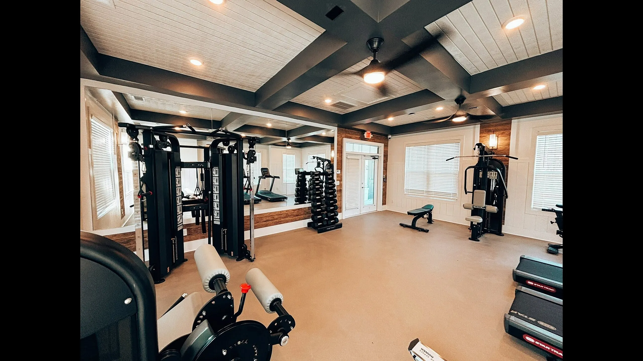Modern apartment gym with state-of-the-art exercise equipment, stylish mirrors, and abundant natural light.