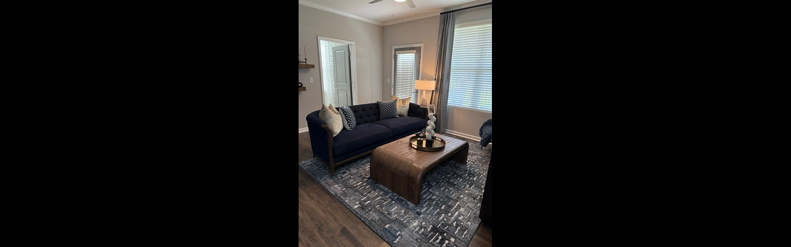 Cozy living room featuring a chic dark blue sofa, stylish wooden coffee table, and elegant decor with large windows for natural light.