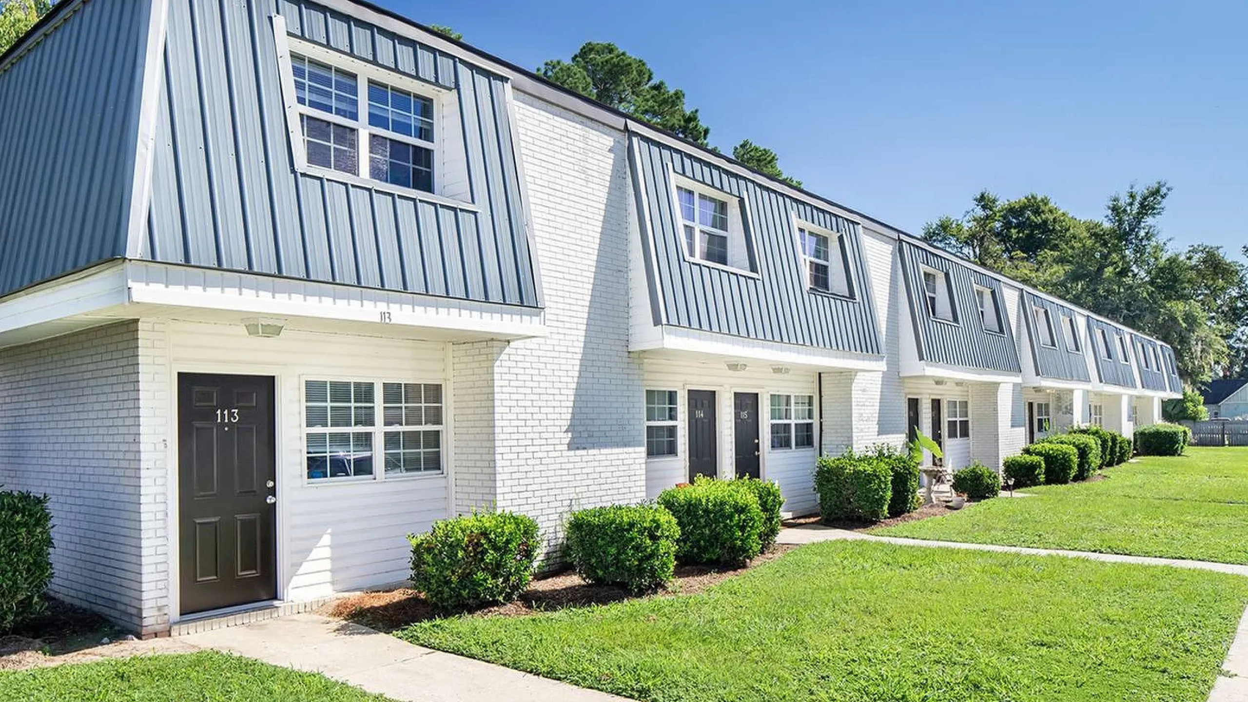 Charming townhouse complex with modern exterior, lush green lawns, and inviting entrances in a tranquil neighborhood.