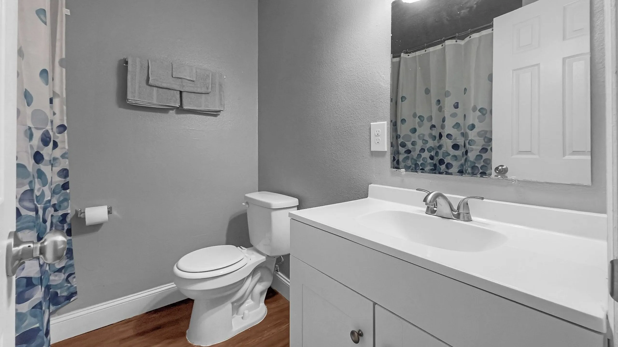 Modern bathroom with elegant white fixtures, a sleek vanity, and vibrant polka dot shower curtain, offering a fresh and inviting space.