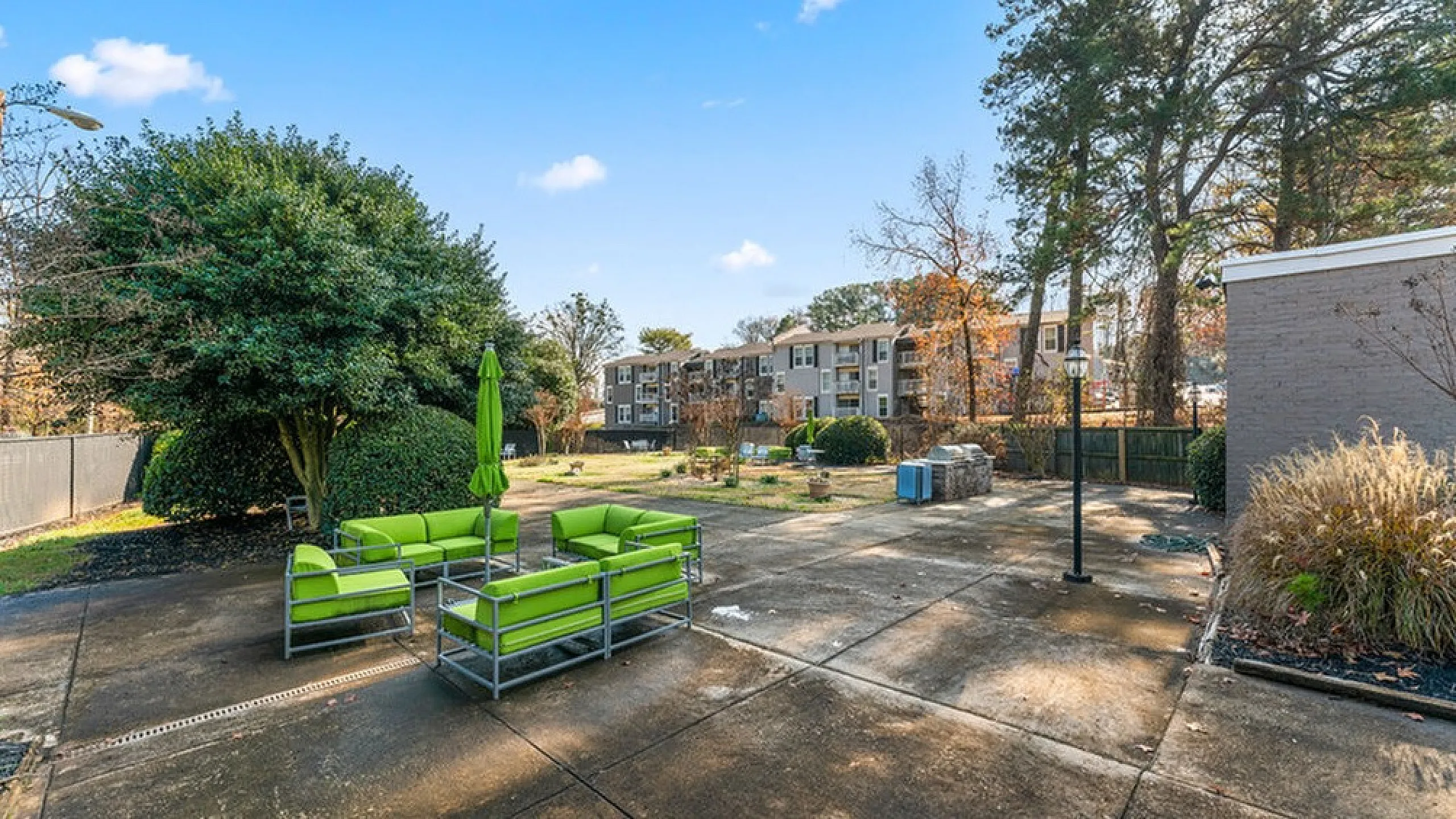 Inviting outdoor patio with vibrant green seating, set against a backdrop of lush greenery and modern apartment buildings.