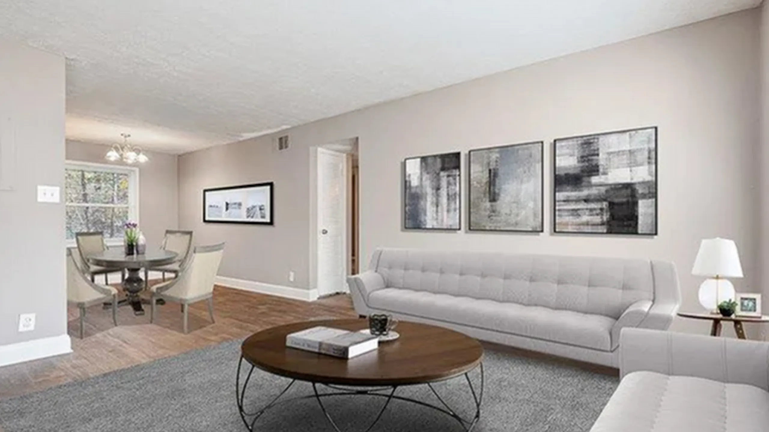Elegant living room with modern decor, featuring cozy gray sofas, a chic round coffee table, and an inviting open dining area.
