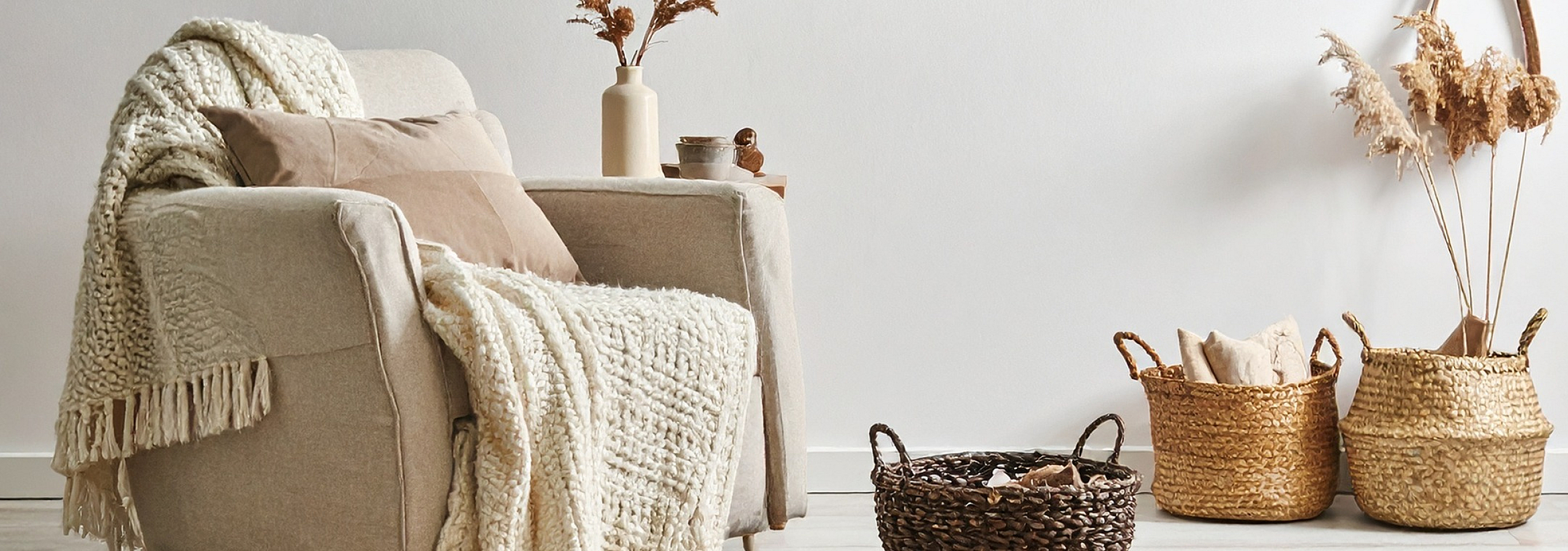 Cozy living space with a plush armchair draped in a soft knit throw, surrounded by chic wicker baskets and elegant decor, exuding warmth and style.
