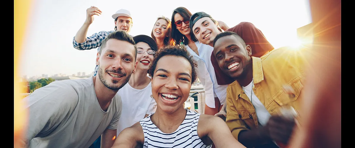 Joyful group of friends enjoying sunny day, capturing memories with smiles and laughter.