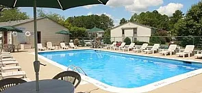 Inviting outdoor pool area with sun loungers and umbrellas, perfect for relaxation in a serene residential setting.